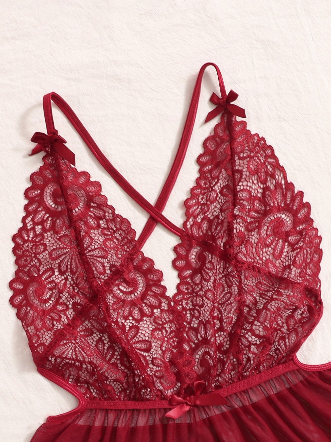 Sheer mesh teddy bodysuit lingerie with contrast lace detailing, spaghetti straps, criss-cross back, backless design, bow accent, and V-string cut.