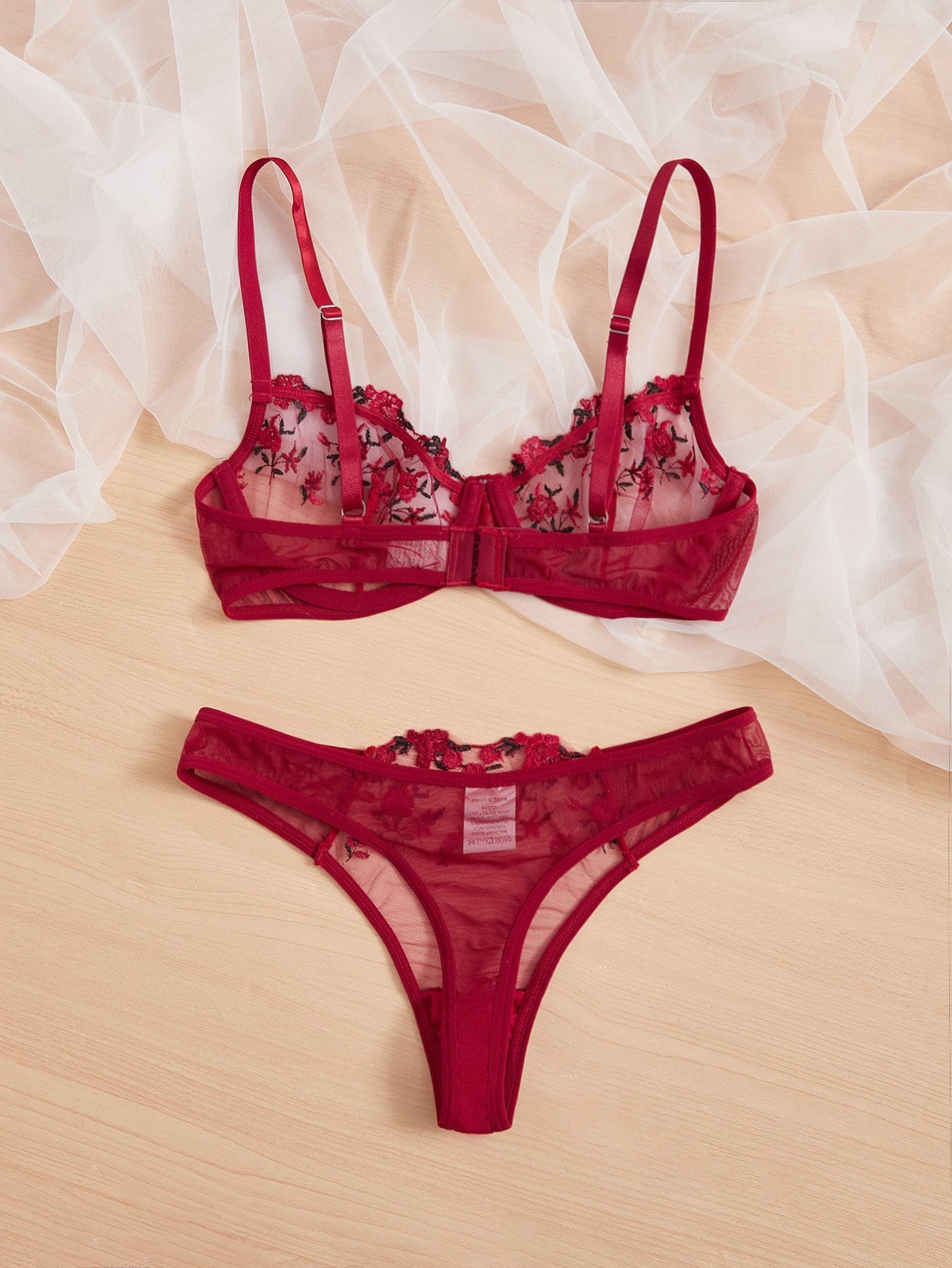 Two-piece women’s lingerie set with embroidered sheer mesh underwire balconette bra and matching mid-rise thong, featuring adjustable straps and slight stretch. Available in Black and Burgundy.