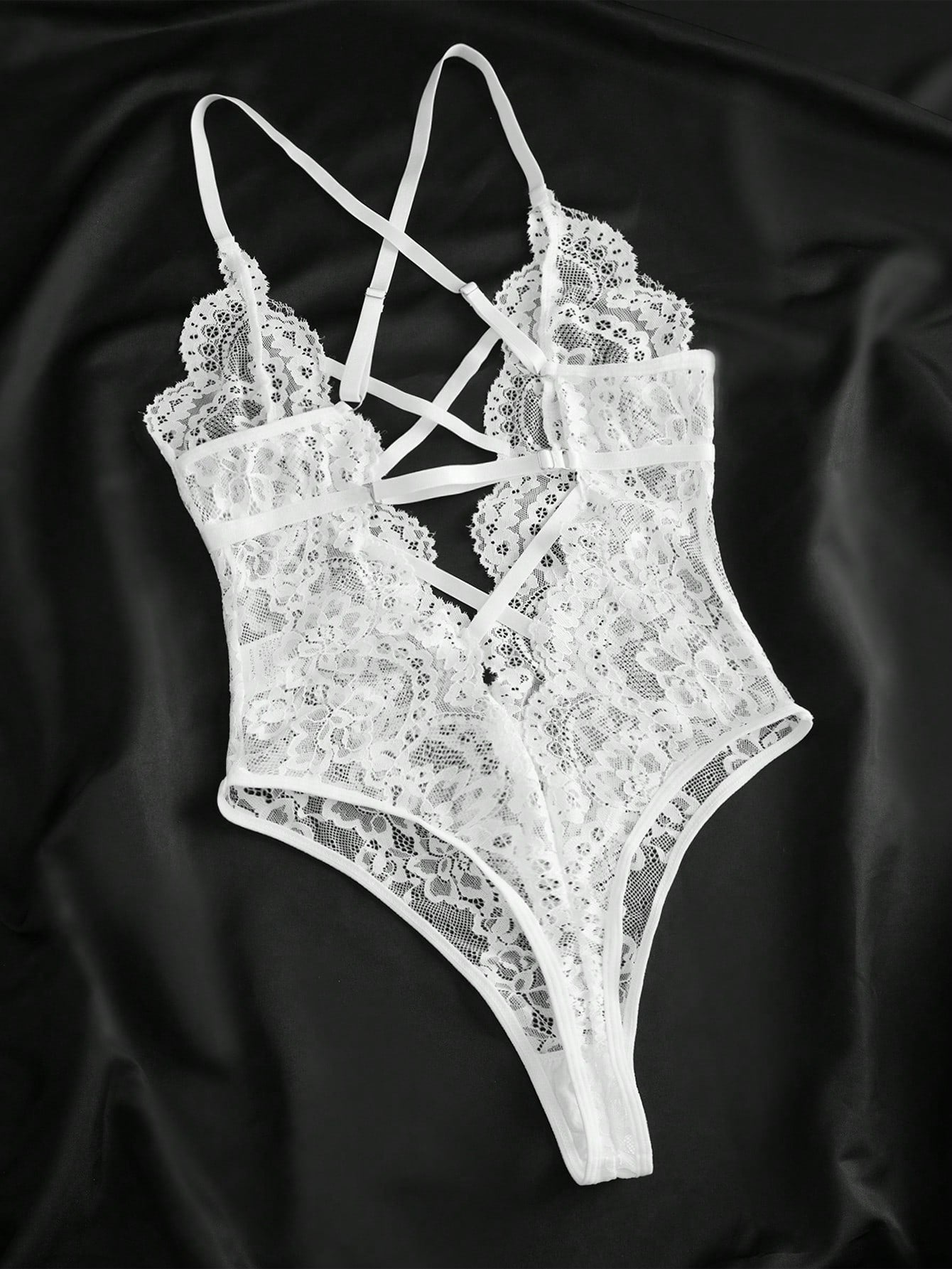 Women’s lace bodysuit featuring a criss-cross back, backless design, spaghetti straps, cut-out accents, and scalloped trim.
