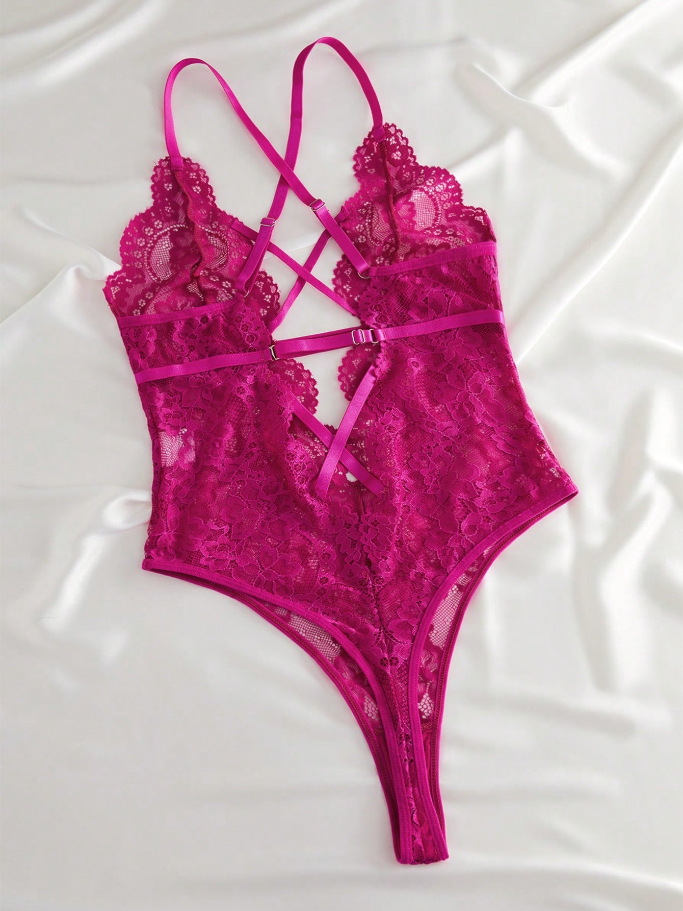 Women’s lace bodysuit featuring a criss-cross back, backless design, spaghetti straps, cut-out accents, and scalloped trim.