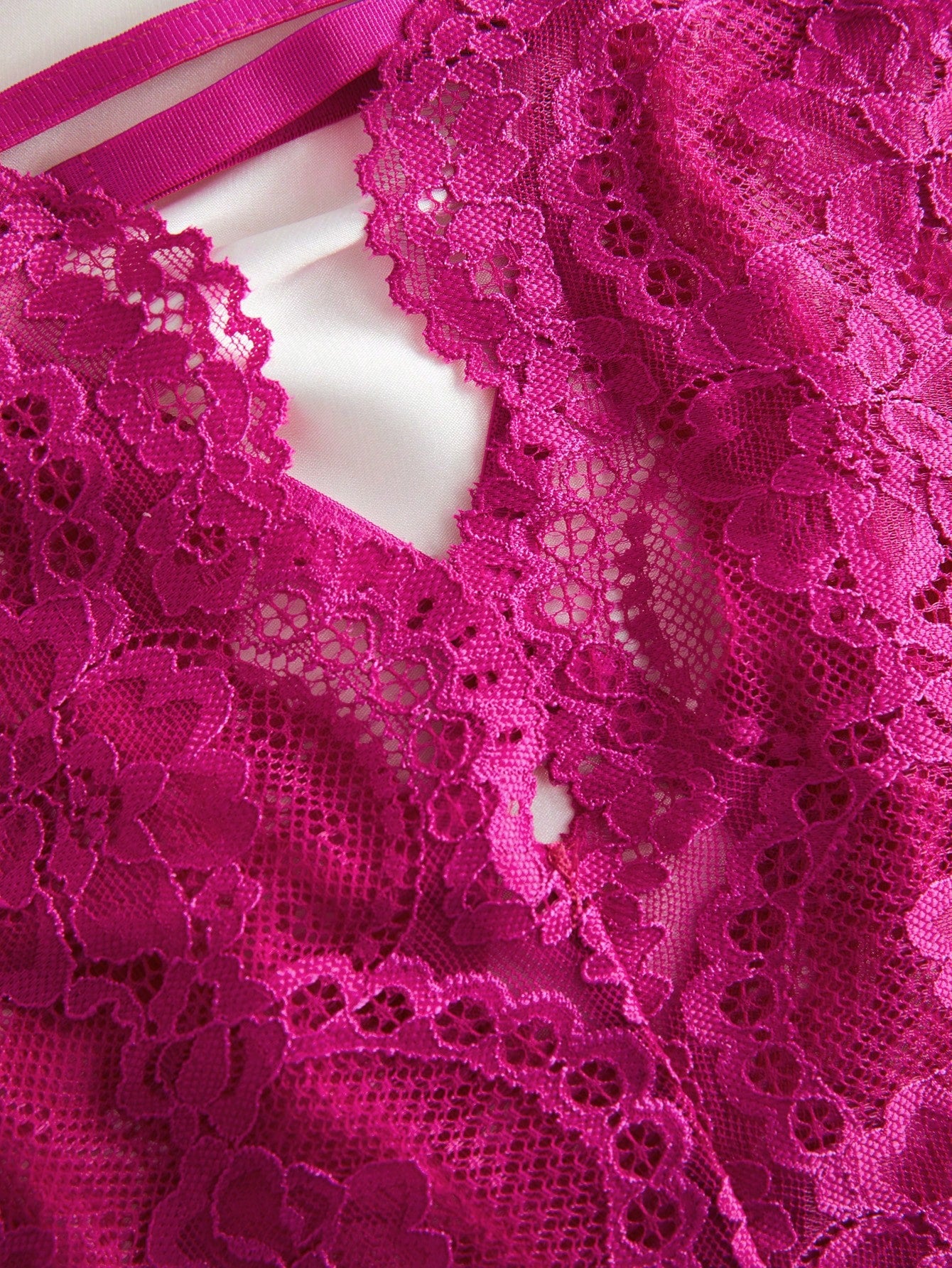 Women’s lace bodysuit featuring a criss-cross back, backless design, spaghetti straps, cut-out accents, and scalloped trim.
