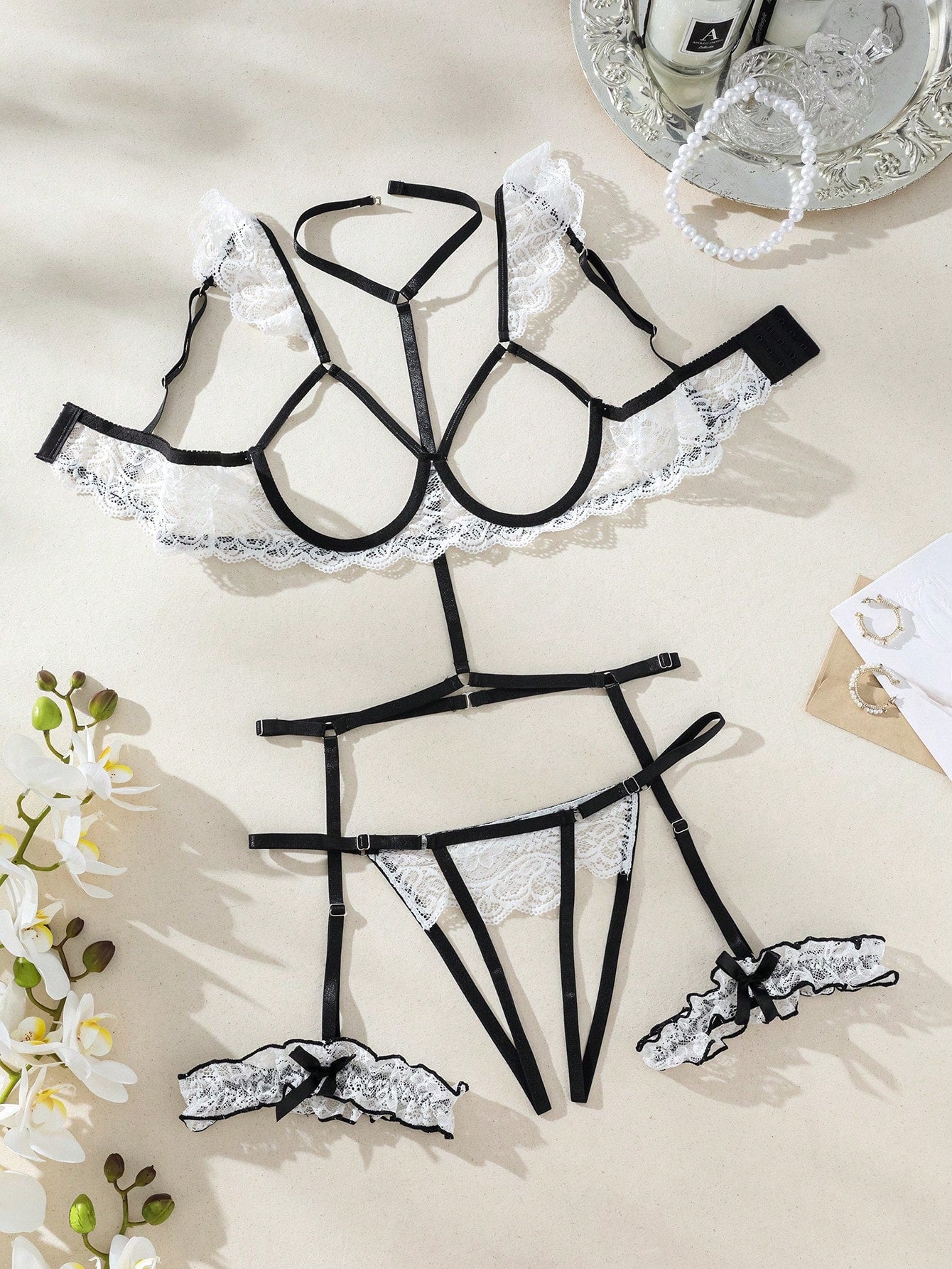 Two-piece white floral lace lingerie set with underwire cups, spaghetti straps, and matching V-string panty with garter-style details; sheer fabric with slight stretch.