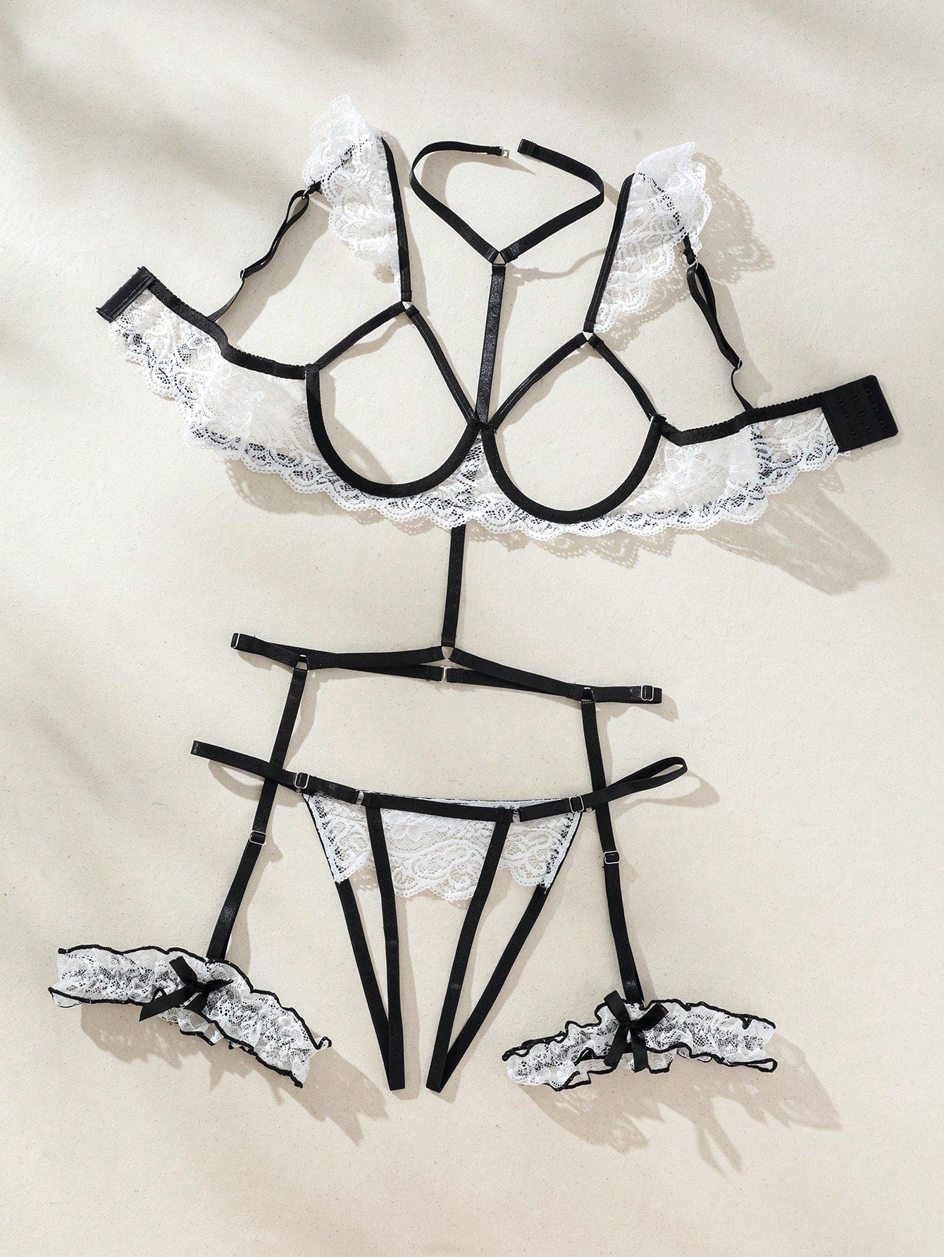 Two-piece white floral lace lingerie set with underwire cups, spaghetti straps, and matching V-string panty with garter-style details; sheer fabric with slight stretch.