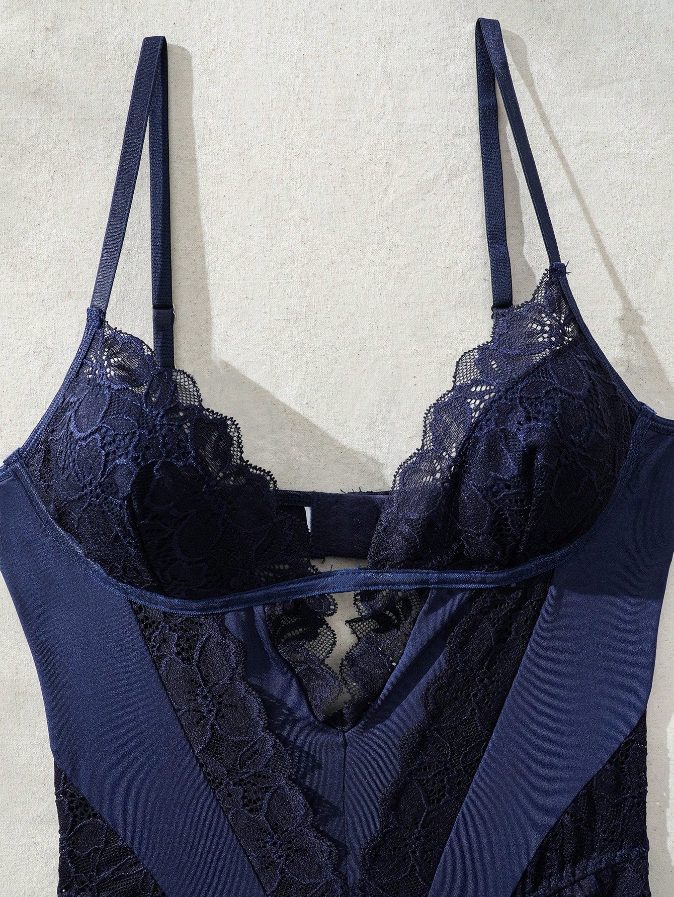 Women's lace bodysuit lingerie featuring a backless design, contrast lace, criss-cross detail, adjustable spaghetti straps, underwire full cups, and a high-rise thong fit.