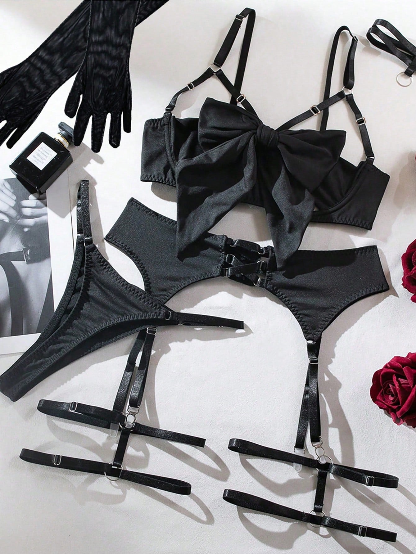 Black women's lingerie set with sheer hollow design, bowknot detail, adjustable spaghetti straps, plunge triangle cup bra, and matching low-rise briefs in a plain pattern.