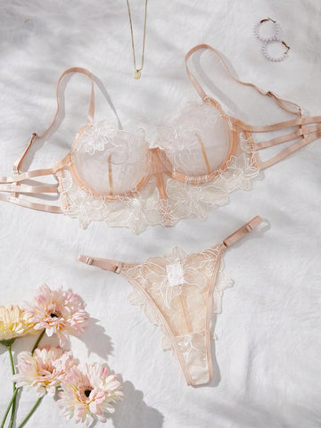 Two-piece women’s lingerie set with a sheer balconette underwire bra featuring adjustable straps and matching low-rise thong panty with embroidery and cut-out details.