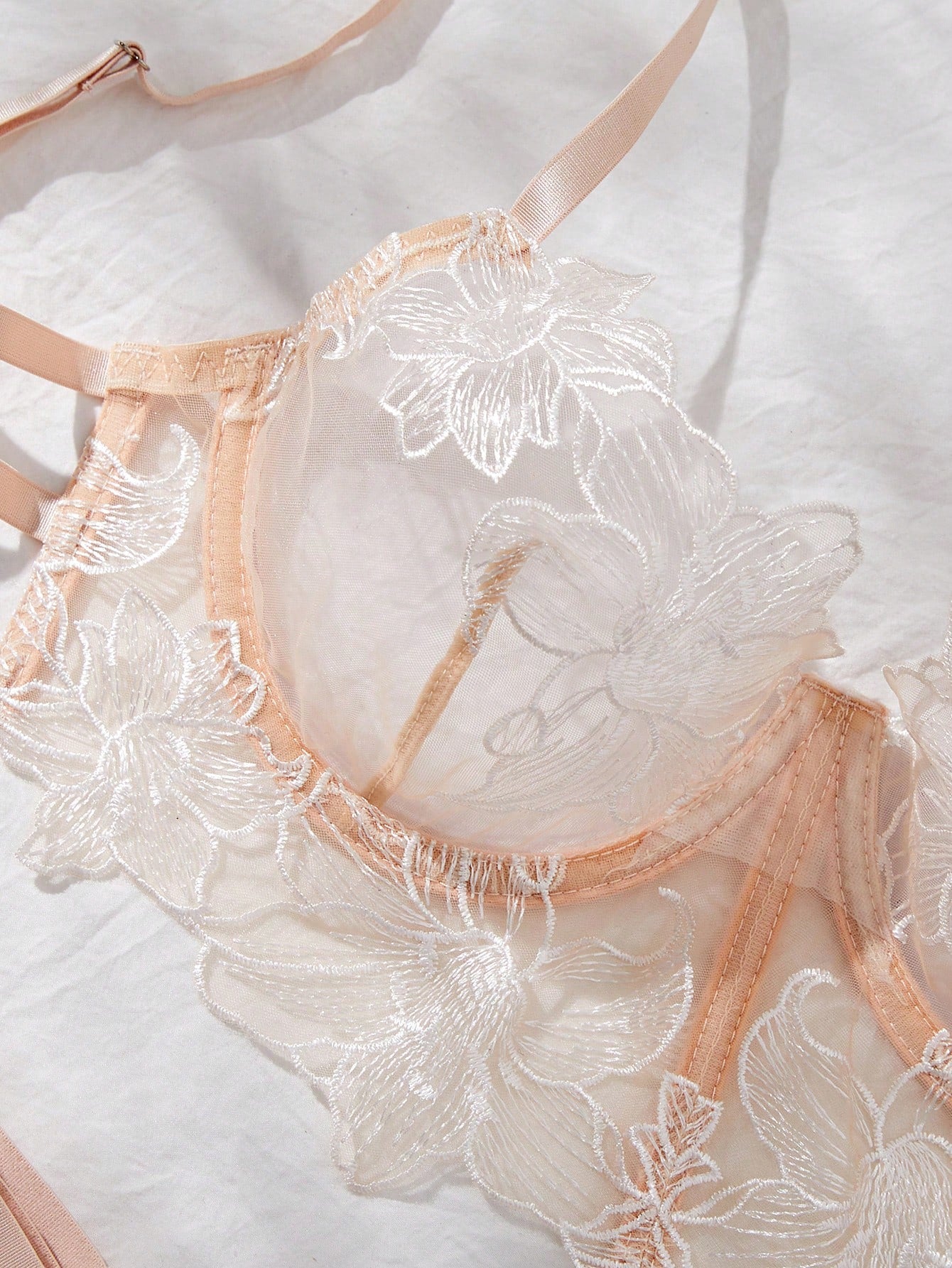 Two-piece women’s lingerie set with a sheer balconette underwire bra featuring adjustable straps and matching low-rise thong panty with embroidery and cut-out details.