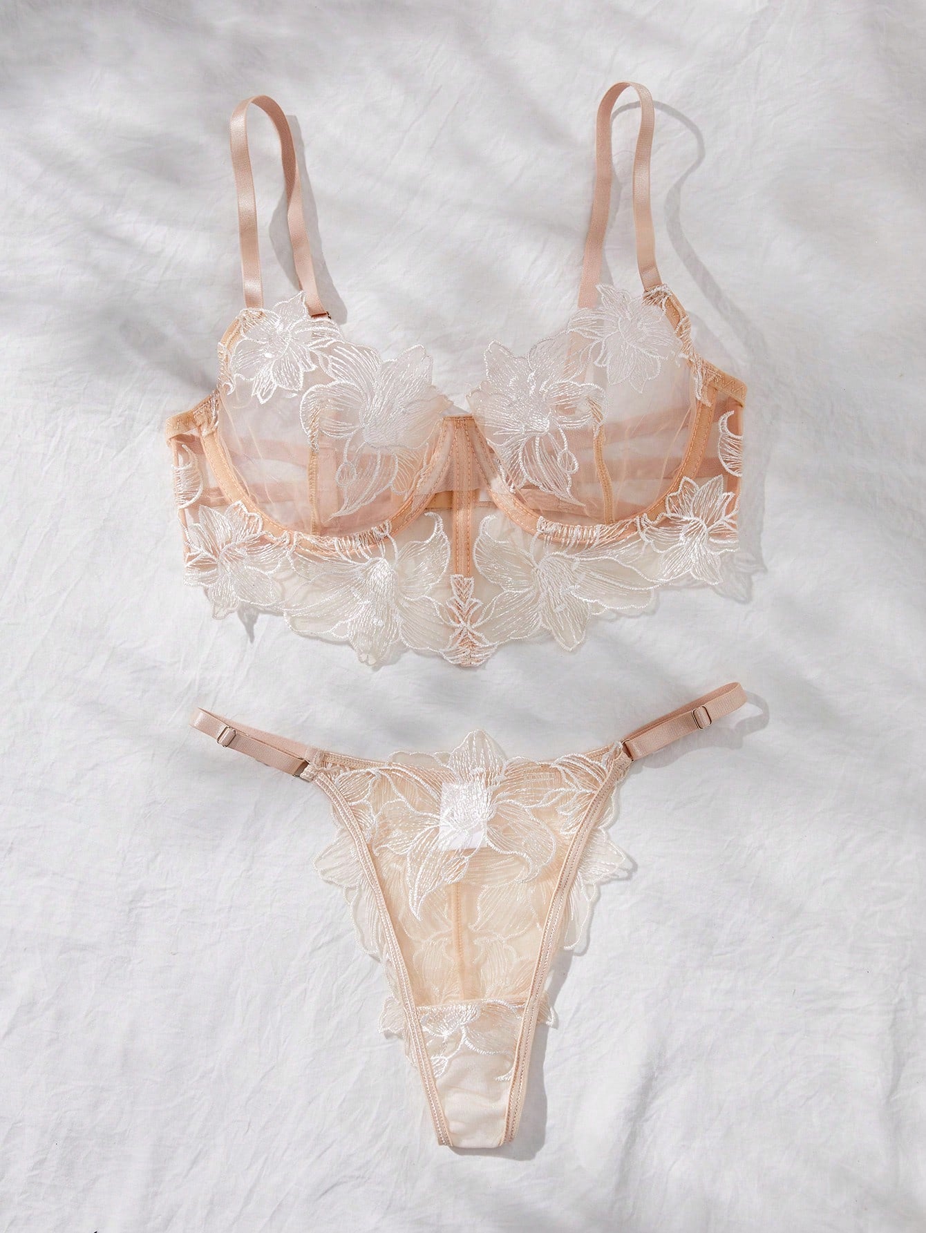 Two-piece women’s lingerie set with a sheer balconette underwire bra featuring adjustable straps and matching low-rise thong panty with embroidery and cut-out details.