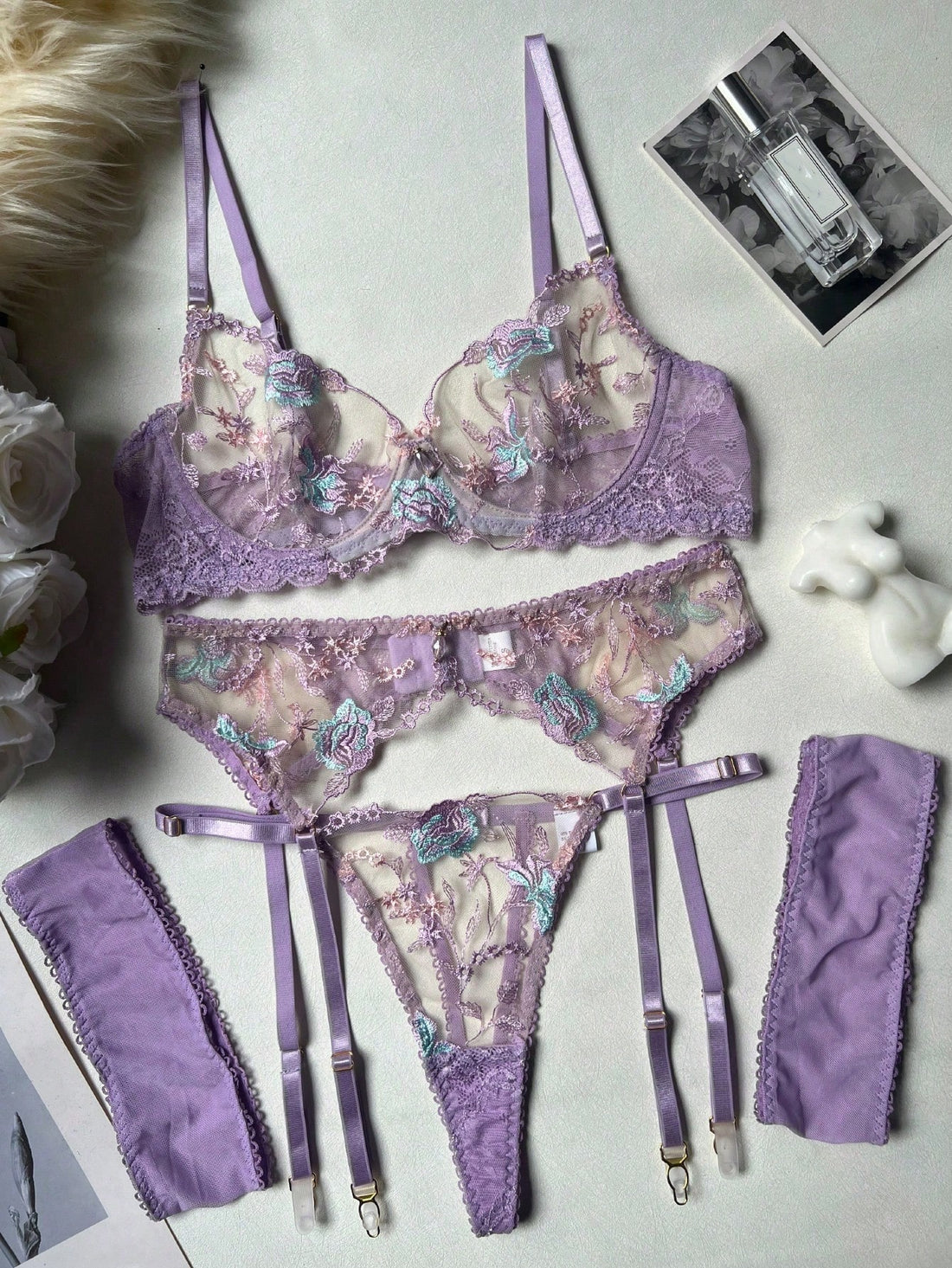 Women's romantic purple lingerie set with embroidered sheer bralette and matching thongs, featuring underwire support, triangle cups, and adjustable spaghetti straps in a 5-piece set.