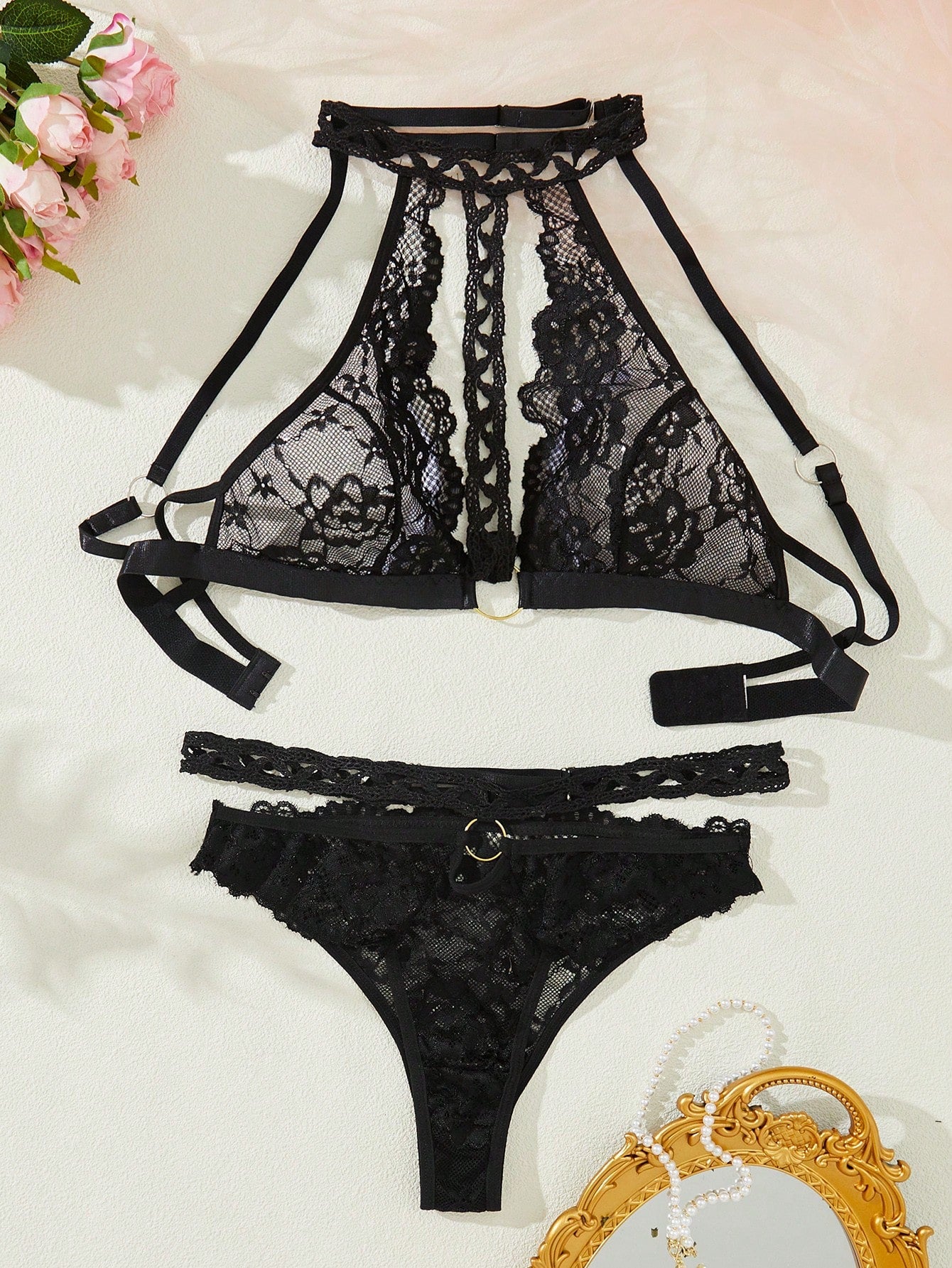Black floral lace ring-linked lingerie set with halter neckline, cut-out details, backless bra, adjustable straps, and matching mid-rise thong in a 2-piece set.