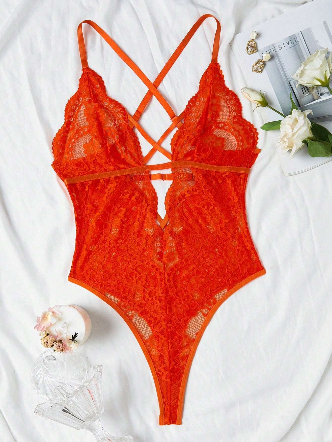 Women’s lace bodysuit featuring a criss-cross back, backless design, spaghetti straps, cut-out accents, and scalloped trim.