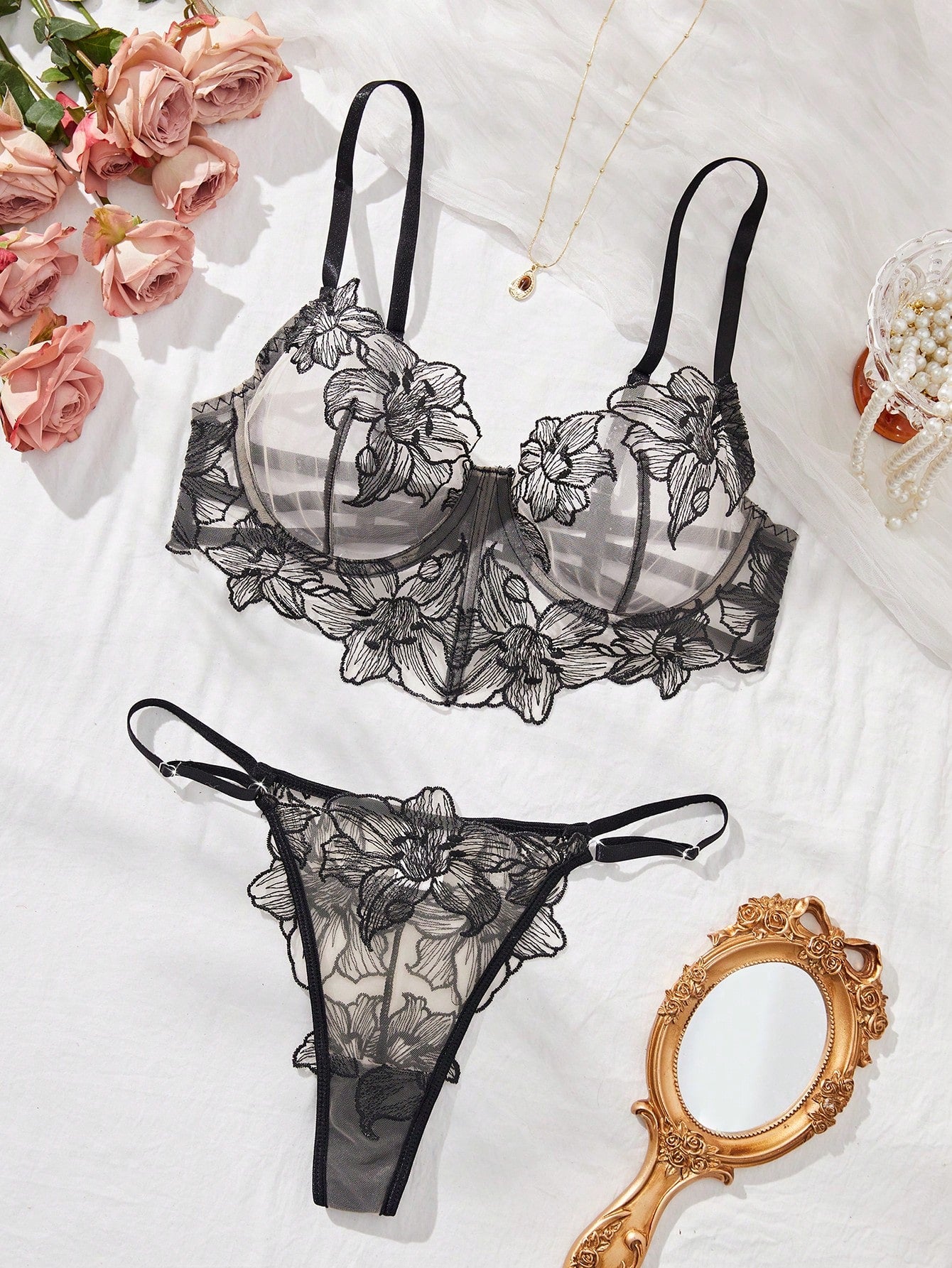 Two-piece women’s lingerie set with a sheer balconette underwire bra featuring adjustable straps and matching low-rise thong panty with embroidery and cut-out details.