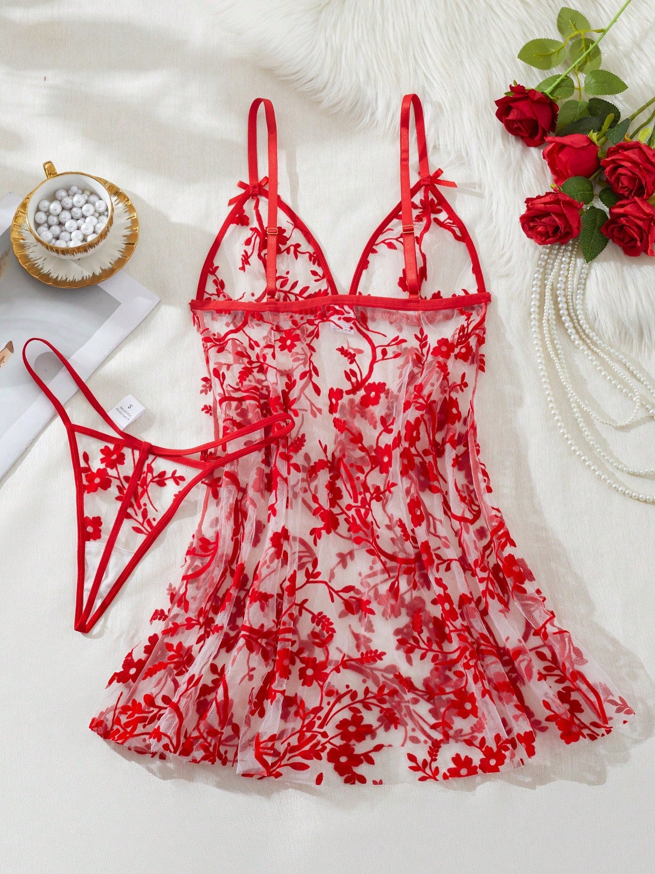 Two-piece women’s floral mesh sleepwear set featuring a front-clasp sheer embroidered bralette with adjustable spaghetti straps and a matching low-rise thong.