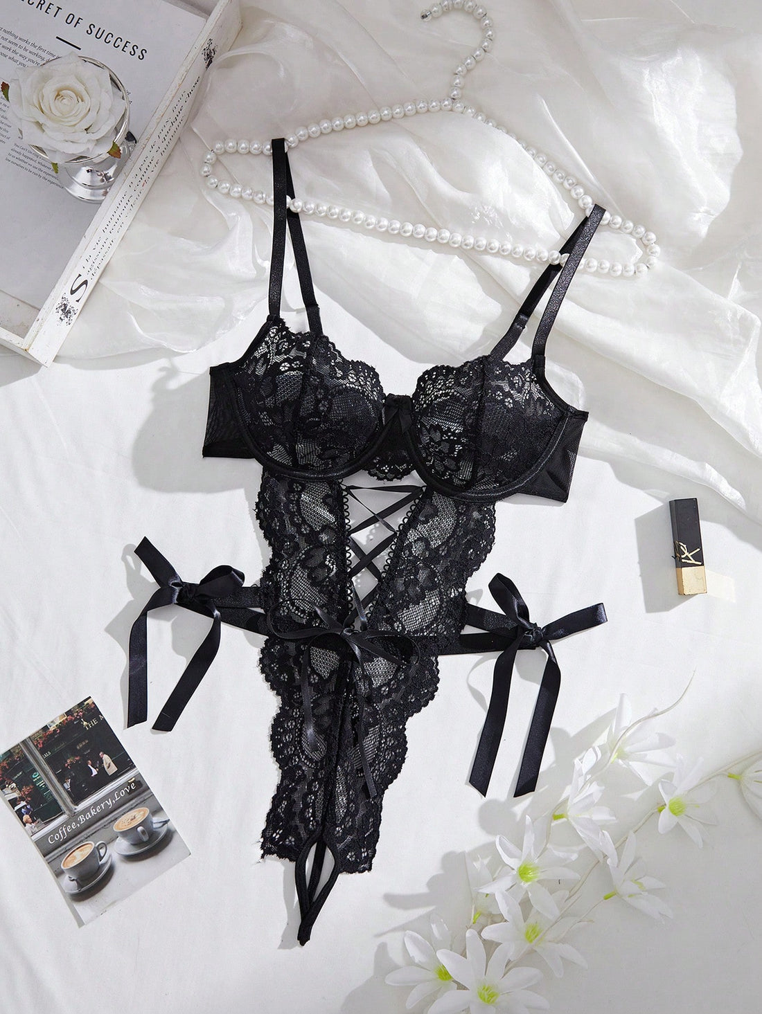 Women’s lace and mesh crotchless lingerie bodysuit with bowknot detail, cut-out accents, adjustable spaghetti straps, underwire support, and thong-style bottom.