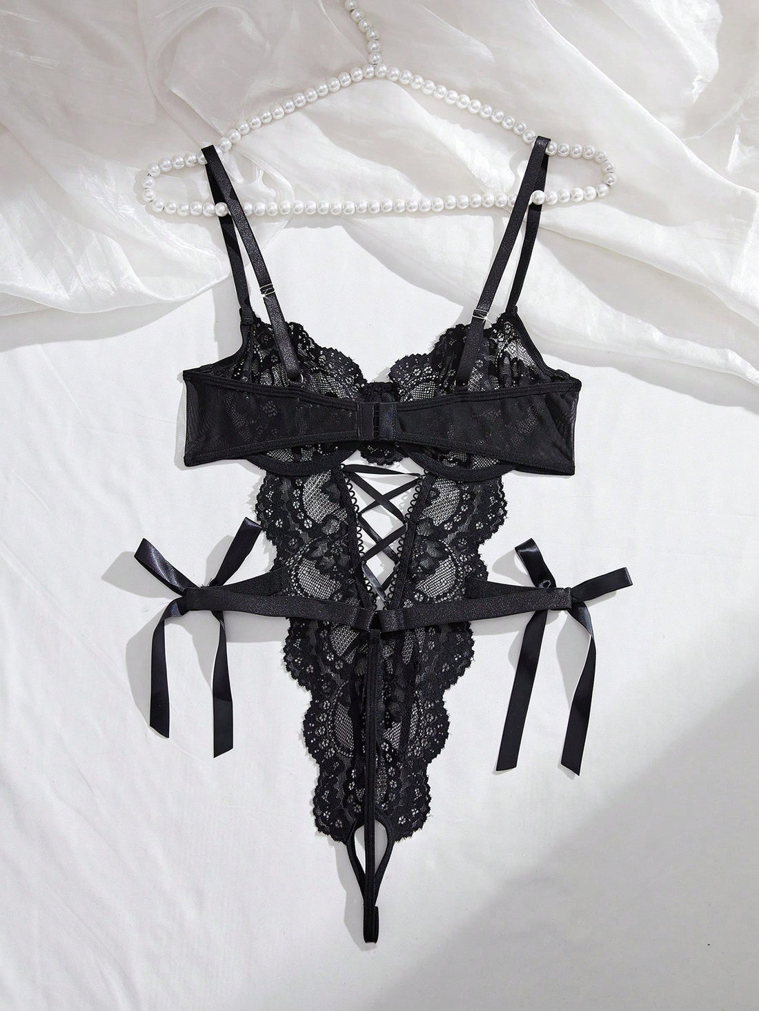 Women’s lace and mesh crotchless lingerie bodysuit with bowknot detail, cut-out accents, adjustable spaghetti straps, underwire support, and thong-style bottom.