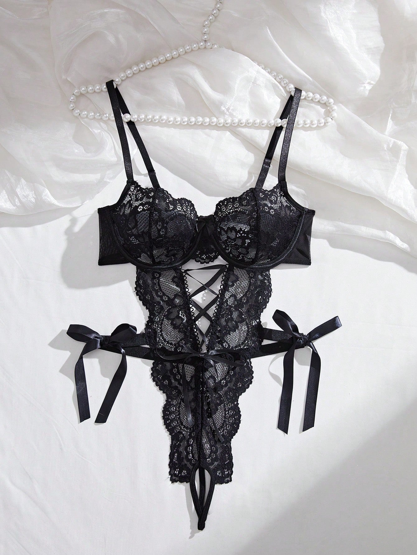Women’s lace and mesh crotchless lingerie bodysuit with bowknot detail, cut-out accents, adjustable spaghetti straps, underwire support, and thong-style bottom.