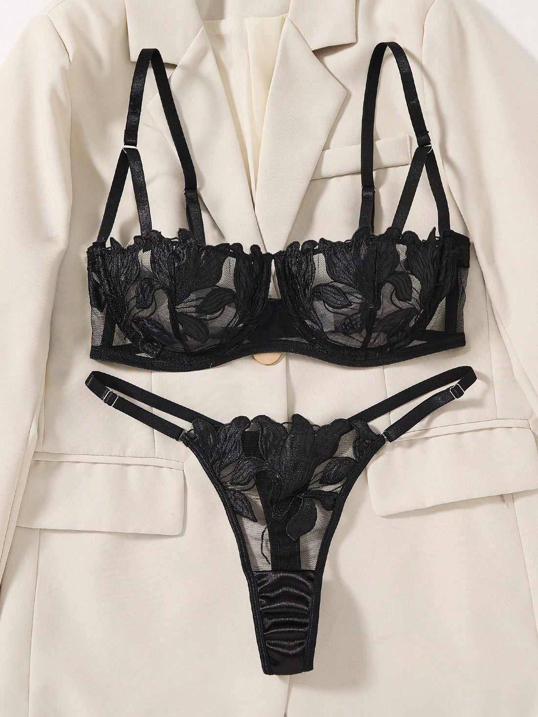 Black 2-piece lingerie set featuring a sheer maple leaf lace semi-cup underwire bra with adjustable straps and matching low-rise thong panty with embroidered floral appliques and cut-out details.
