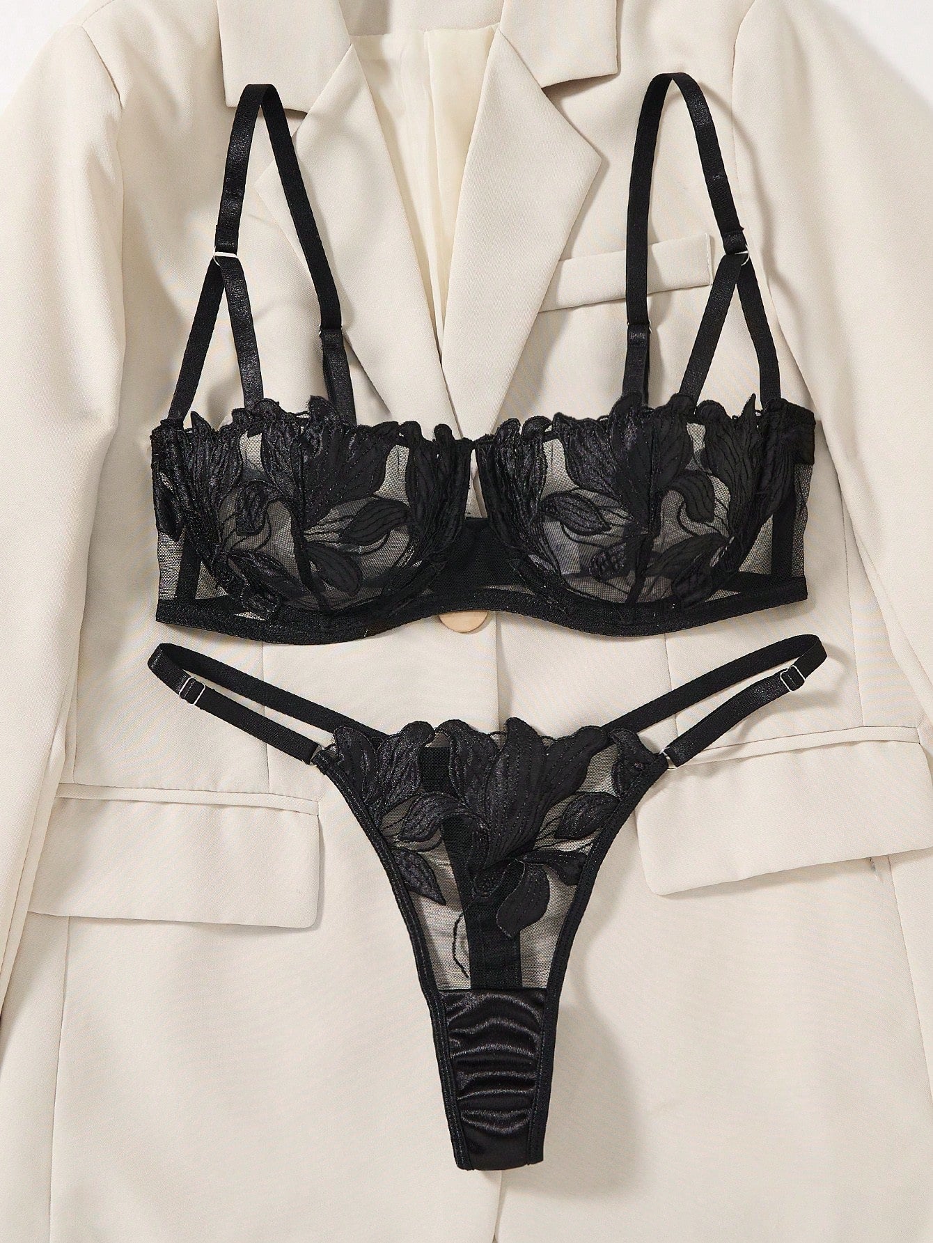 Black 2-piece lingerie set featuring a sheer maple leaf lace semi-cup underwire bra with adjustable straps and matching low-rise thong panty with embroidered floral appliques and cut-out details.