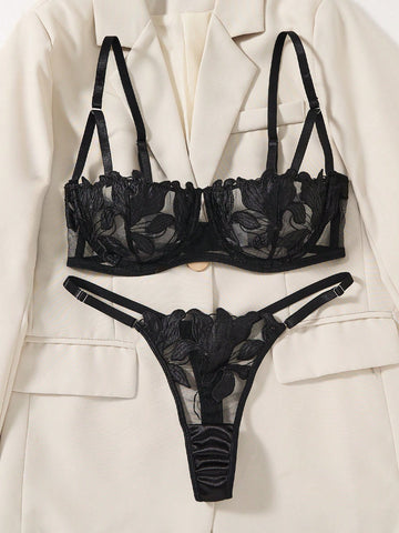 Black 2-piece lingerie set featuring a sheer maple leaf lace semi-cup underwire bra with adjustable straps and matching low-rise thong panty with embroidered floral appliques and cut-out details.