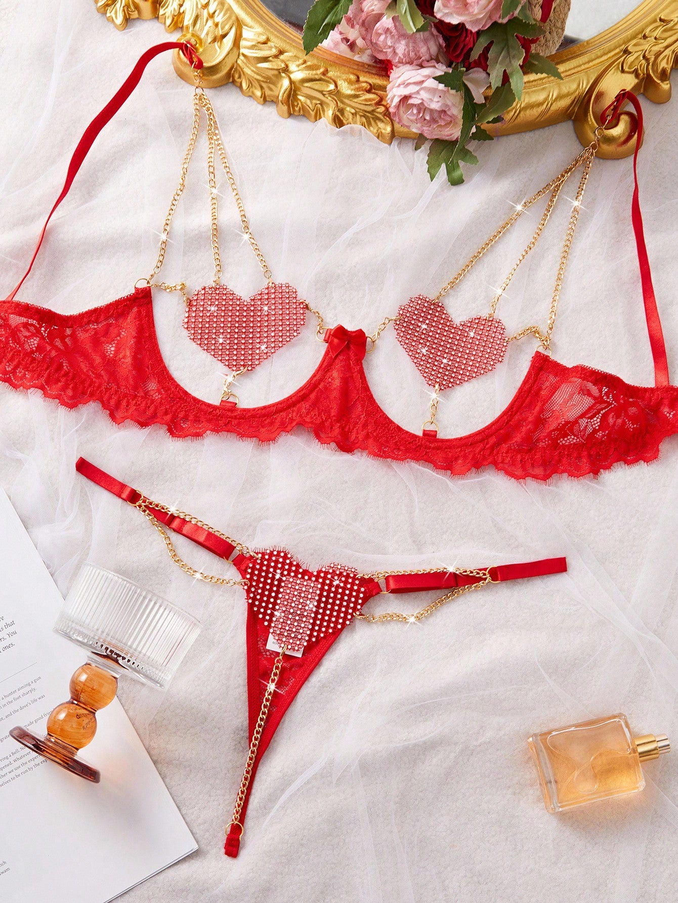 Women’s 2-piece sexy lingerie set featuring rhinestone and chain details, mesh and lace splice design, spaghetti straps, and a low-rise thong bottom; shown in black and red options.