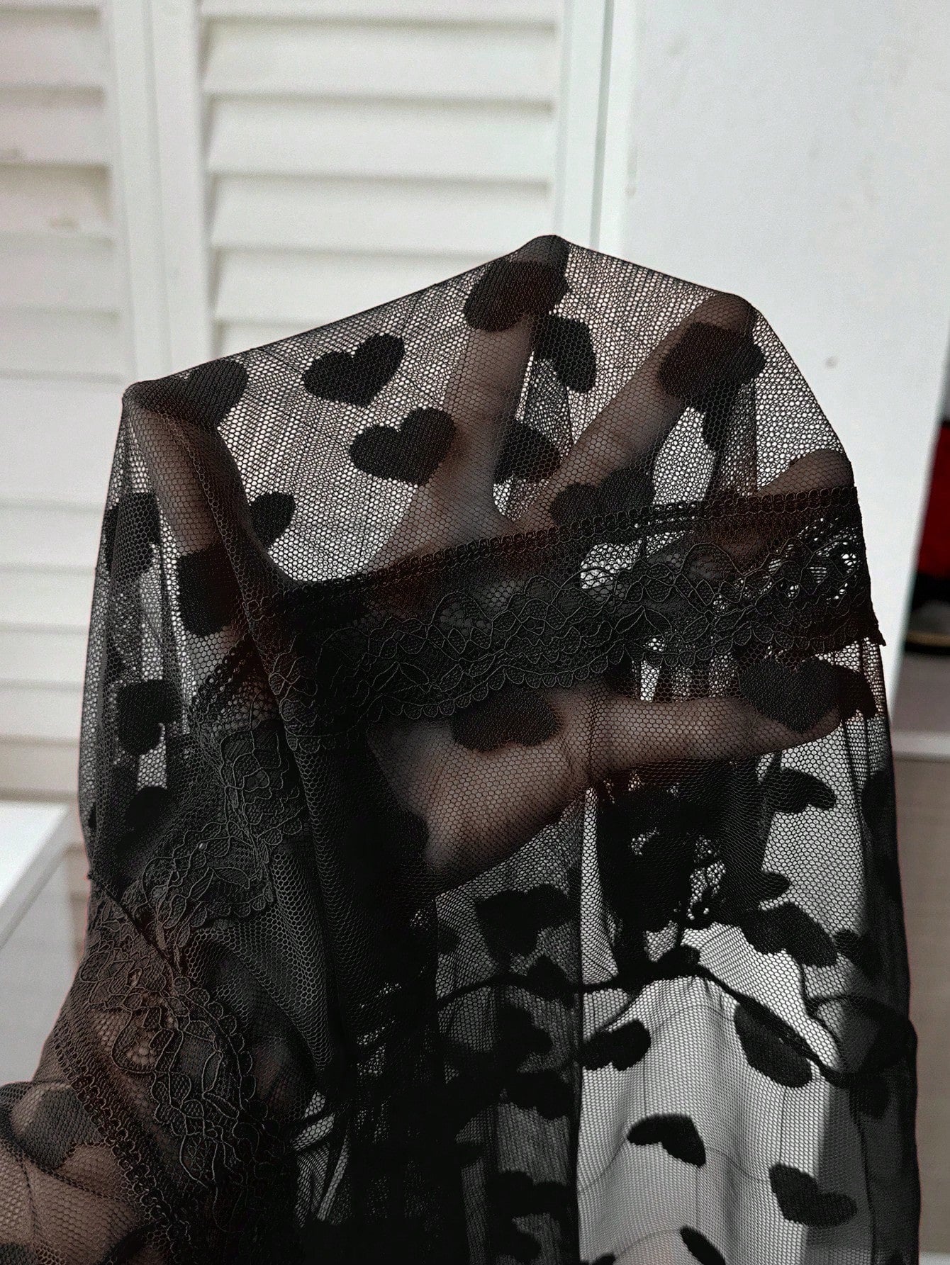 Black sheer mesh mini slip dress with spaghetti straps, bow detail, and contrast lace trim in a slim fit silhouette.
