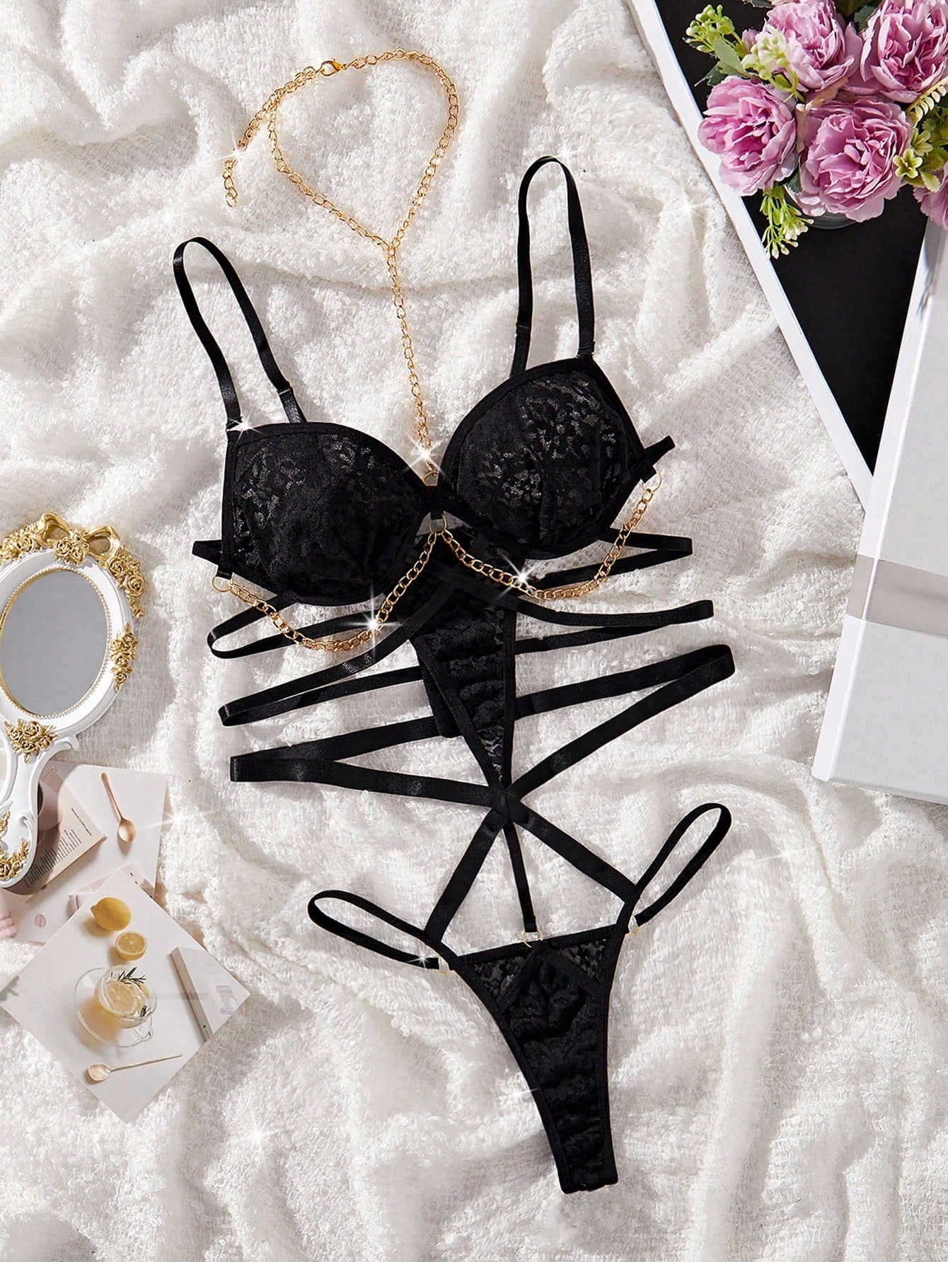 Black lace teddy bodysuit lingerie with chain-linked cut-out detail, underwire cups, spaghetti adjustable straps, sleeveless design, and thong-style bottom.