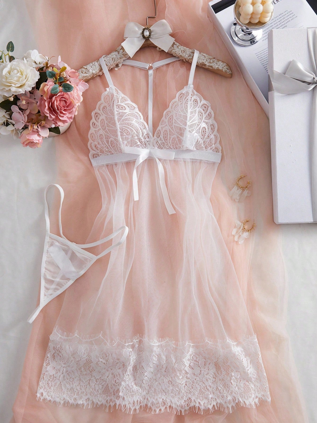 Two-piece white lace and mesh babydoll lingerie set featuring a short sleeveless nightgown with spaghetti straps and crossback detail, plus a matching low-rise V-string panty.
