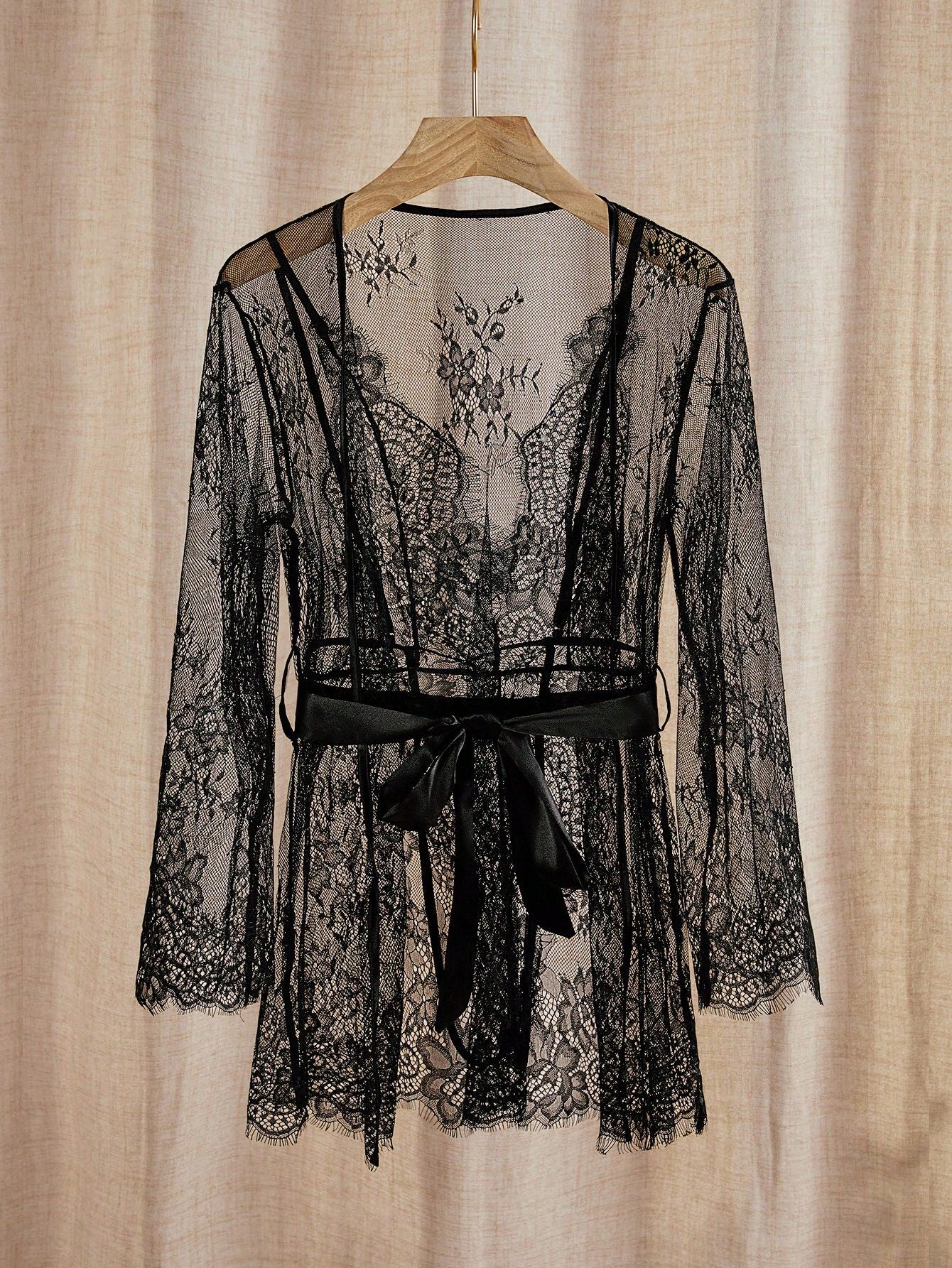 Black women’s lingerie set with a semi-sheer lace bodysuit and matching short long-sleeve robe, featuring adjustable spaghetti straps, belted detail, and a classic sexy look.
