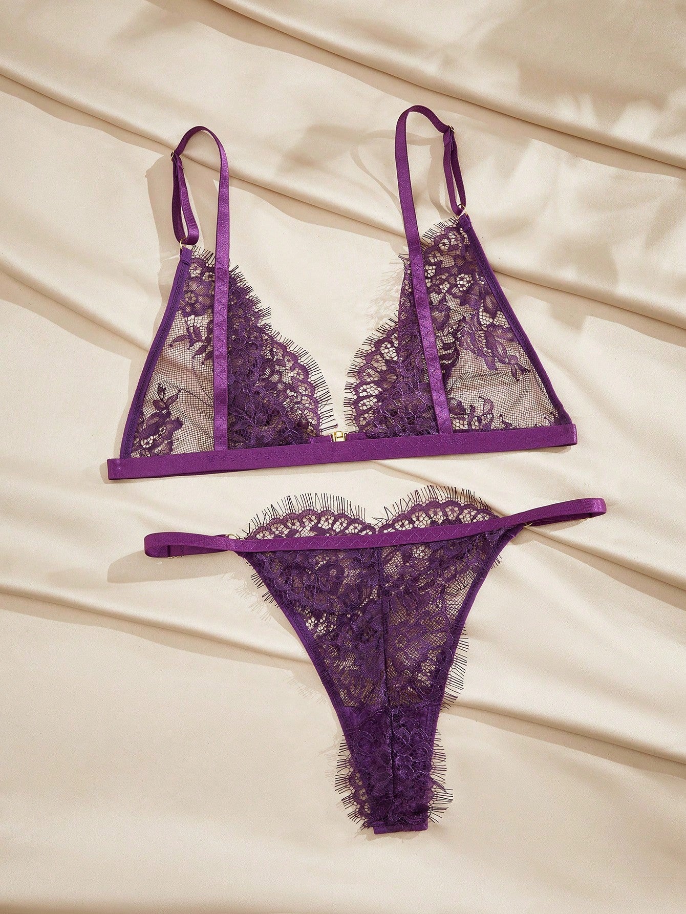 Women's purple lace lingerie set with wireless triangle bra, adjustable spaghetti straps, and matching mid-rise thong