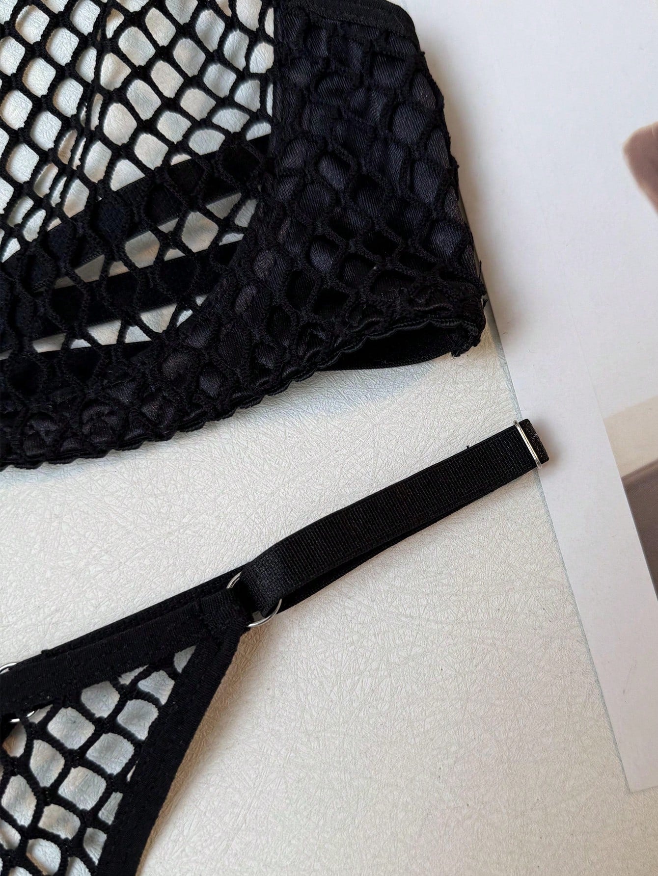 Black 2-piece ladies' lingerie set with hollow-out fishnet design, halter underwire top, and low-rise thong; sheer mesh with medium stretch in a plain pattern.