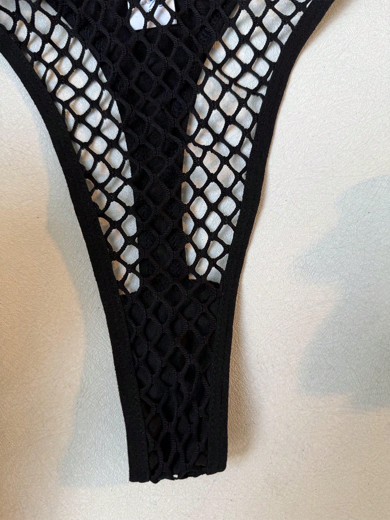 Black 2-piece ladies' lingerie set with hollow-out fishnet design, halter underwire top, and low-rise thong; sheer mesh with medium stretch in a plain pattern.