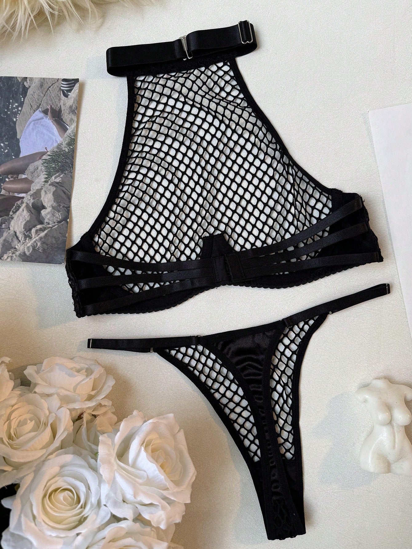 Black 2-piece ladies' lingerie set with hollow-out fishnet design, halter underwire top, and low-rise thong; sheer mesh with medium stretch in a plain pattern.