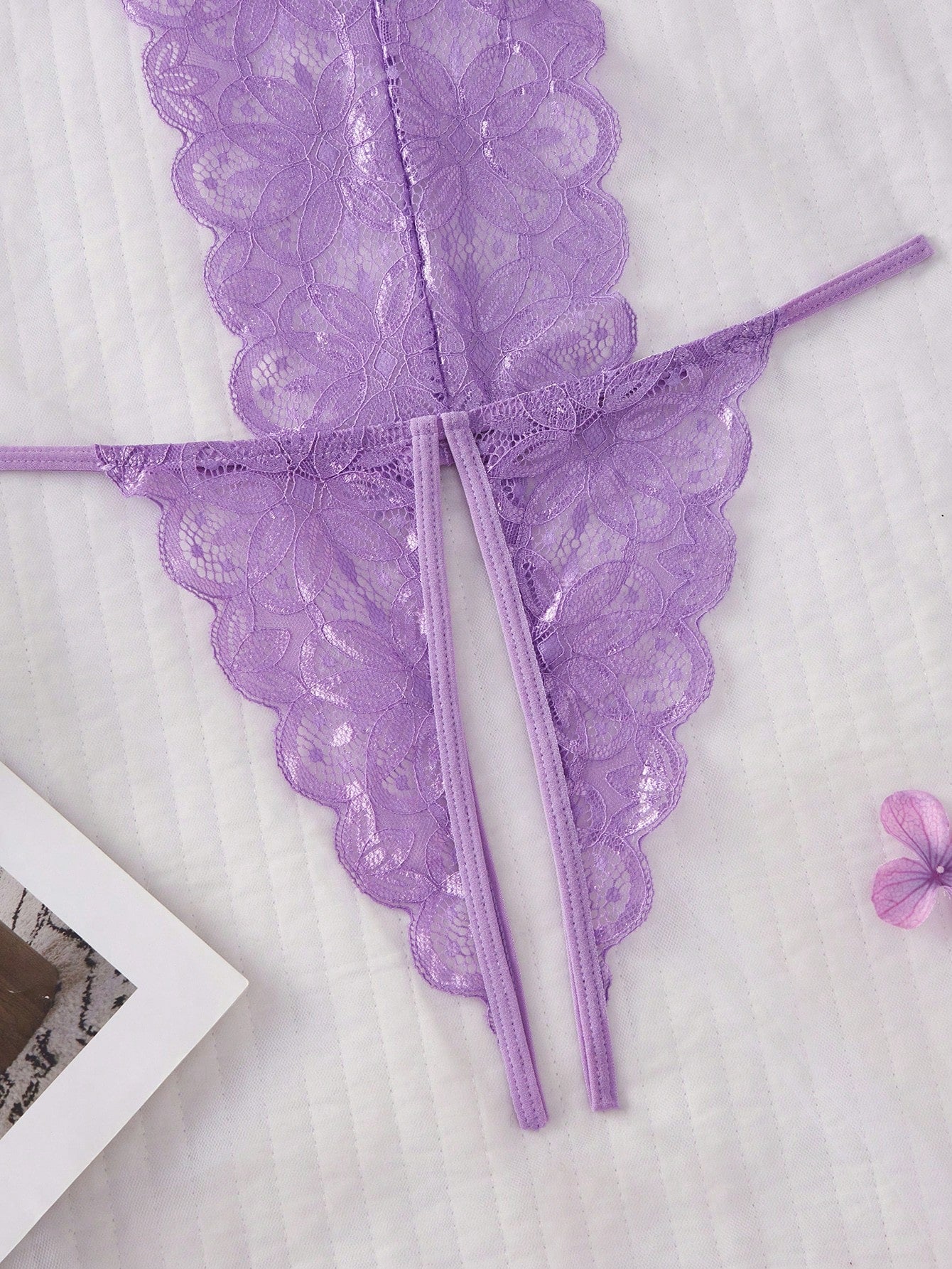 Purple women's sexy lingerie bodysuit with deep V-neck, sheer contrast floral lace, hollow-out details, bow decor, adjustable spaghetti straps, backless design, and crotchless thong-style bottom.
