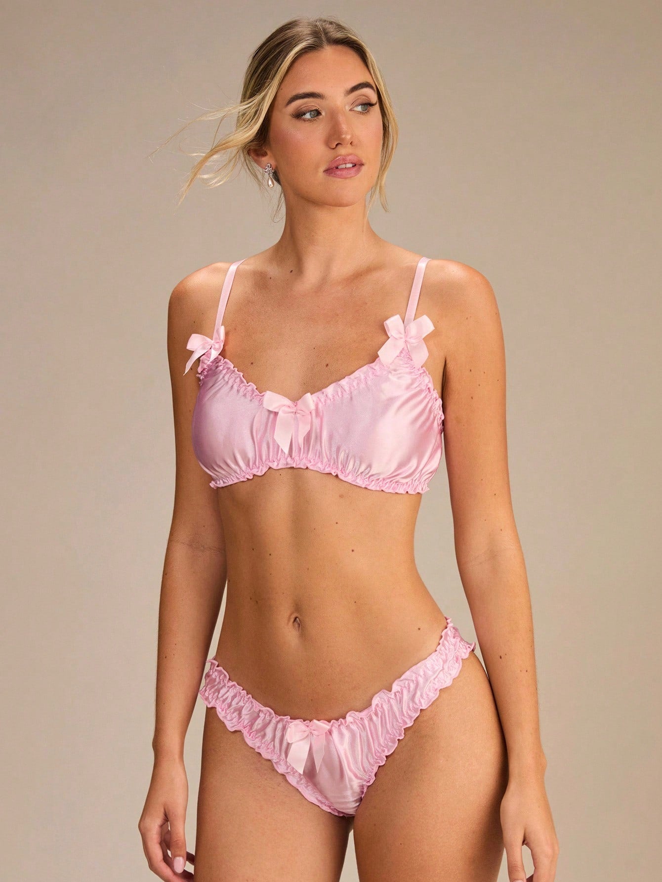 Pink 2-piece women's lingerie set featuring a solid color wire-free bralette with ruffle and bow detail, adjustable straps, and a matching low-rise triangle brief panty.