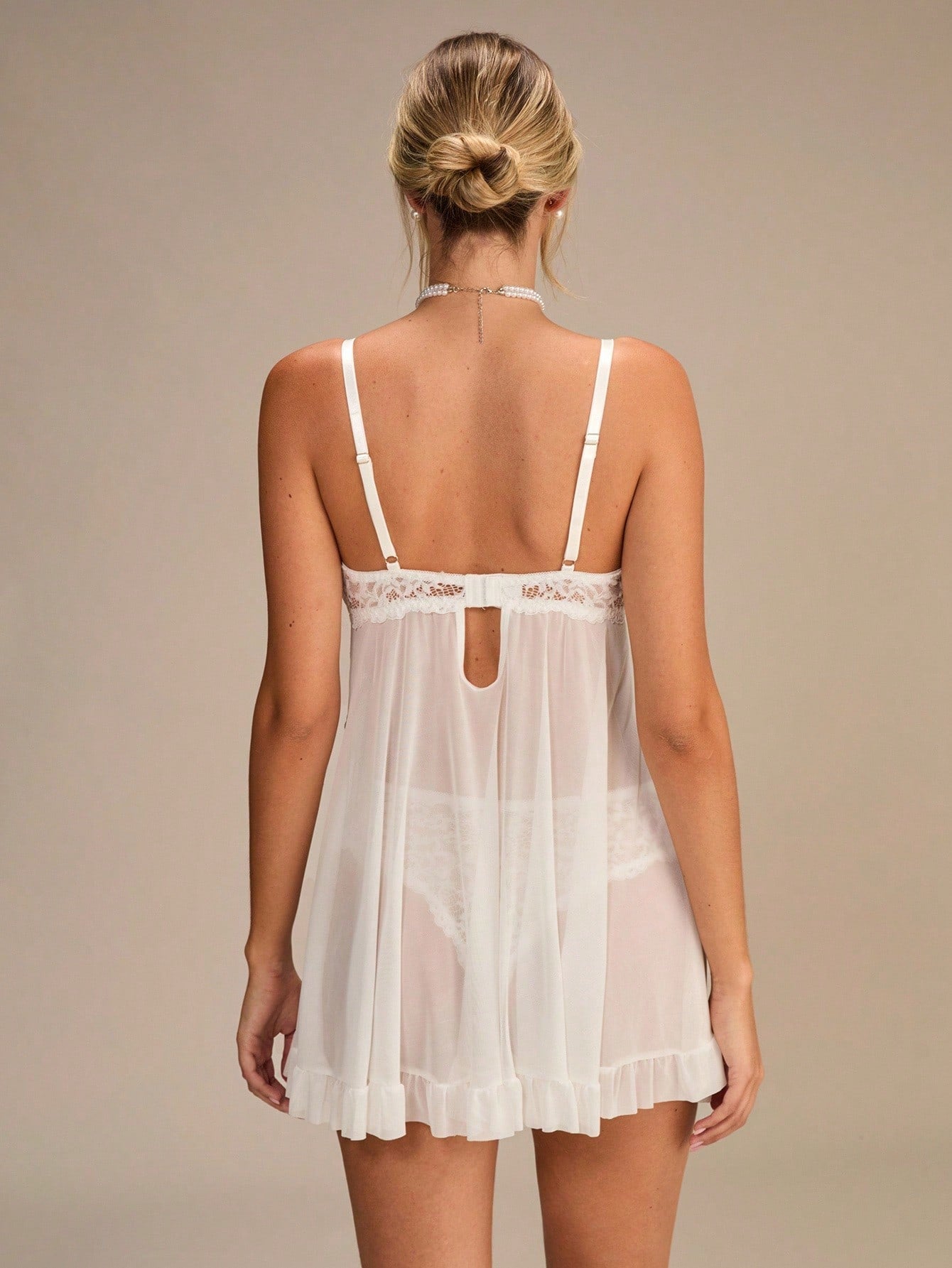 White sheer mesh babydoll lingerie dress featuring contrast lace, ruffle trim, bow front, and spaghetti straps, paired with a matching thong in a 2-piece set.