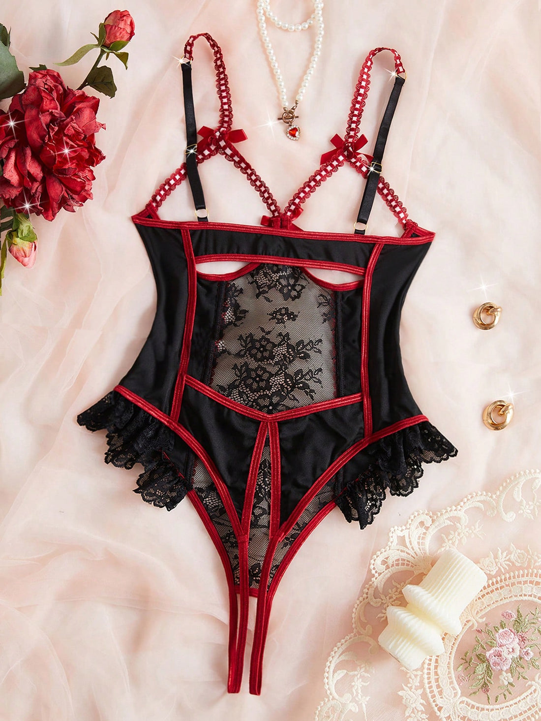 Black sheer floral lace patchwork bodysuit with adjustable spaghetti straps, bow detail, backless cut, hollow accents, and open crotch design.