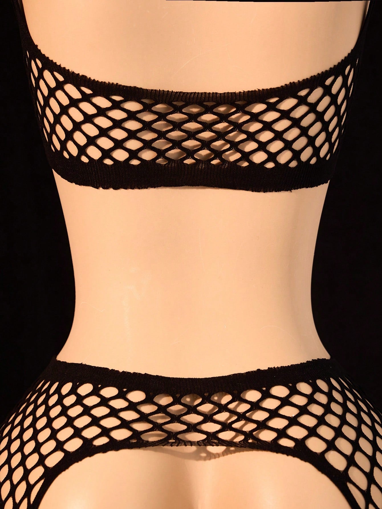 Black 2-piece fishnet lingerie set featuring a sheer wireless bralette with spaghetti straps and matching mini shorts with hollow-out detail; high-stretch fabric in a plain pattern.