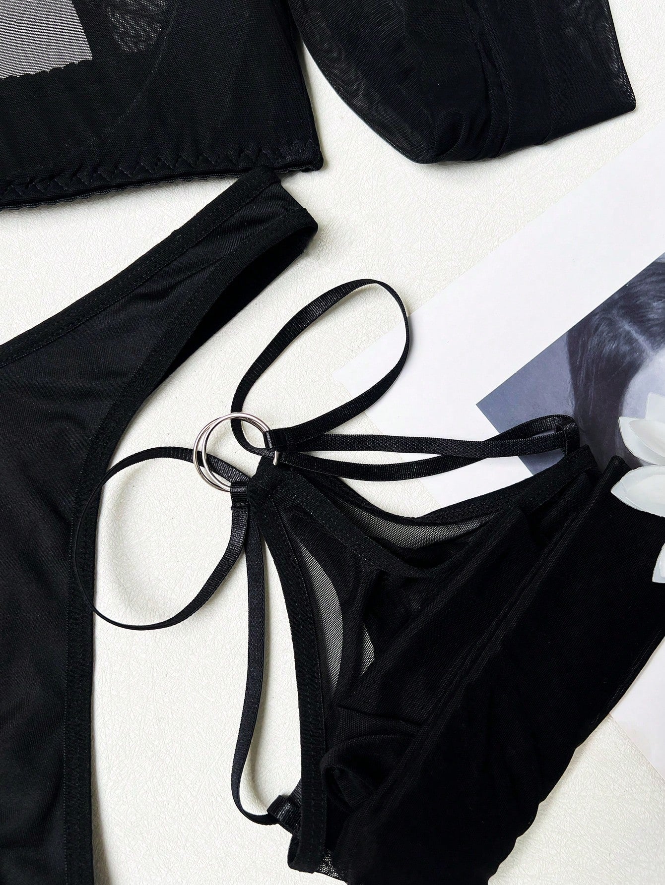 Black sheer lingerie set with a long sleeve cut-out top, thong panty, and matching stockings; includes adjustable spaghetti straps, triangle cups, underwire support, and slight stretch fabric.