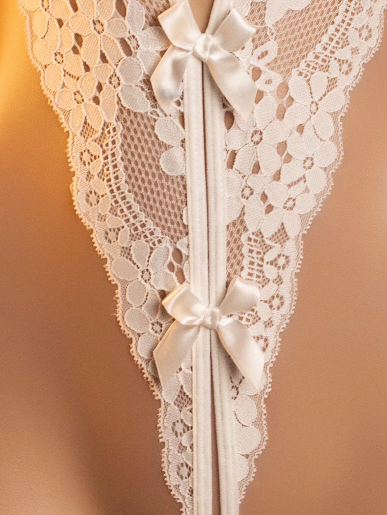 White sheer mesh lingerie romper with a deep V neckline and backless design; sleeveless, wireless, and medium-stretch fabric for a date-night look.