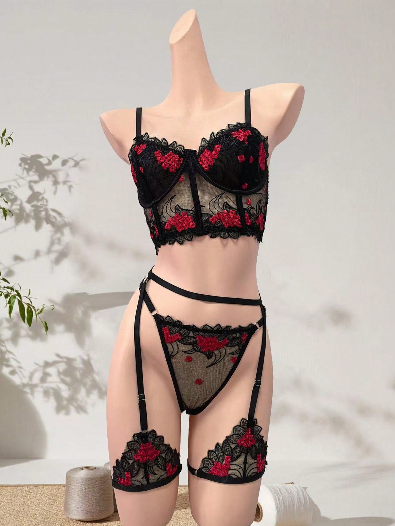 Three-piece women’s lingerie set with floral embroidery and sheer hollow-out design, featuring a longline spaghetti-strap bra with adjustable straps and matching low-rise thong style pieces.
