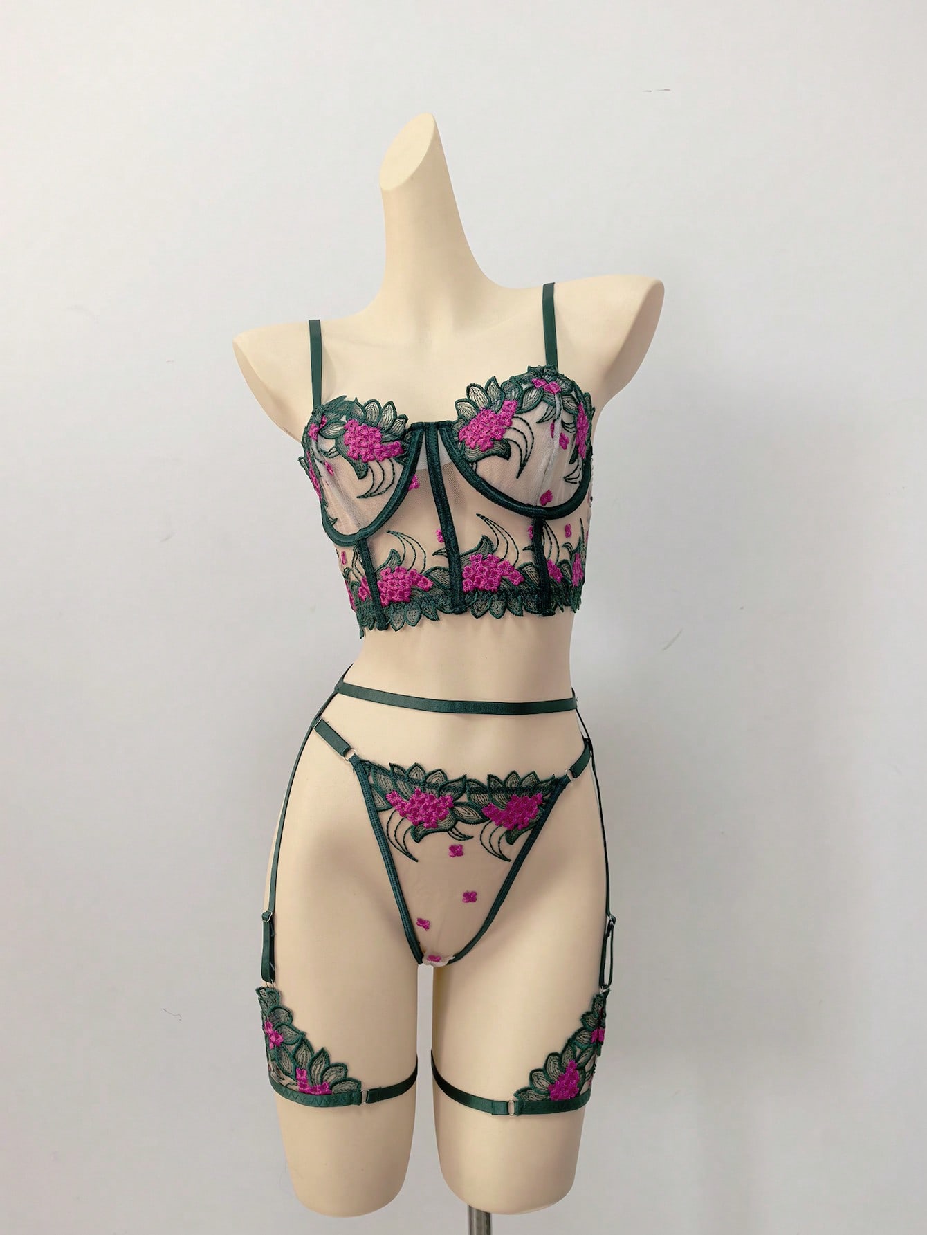 Three-piece women’s lingerie set with floral embroidery and sheer hollow-out design, featuring a longline spaghetti-strap bra with adjustable straps and matching low-rise thong style pieces.