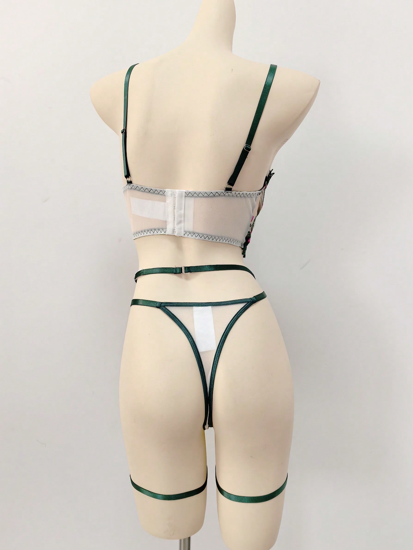 Three-piece women’s lingerie set with floral embroidery and sheer hollow-out design, featuring a longline spaghetti-strap bra with adjustable straps and matching low-rise thong style pieces.