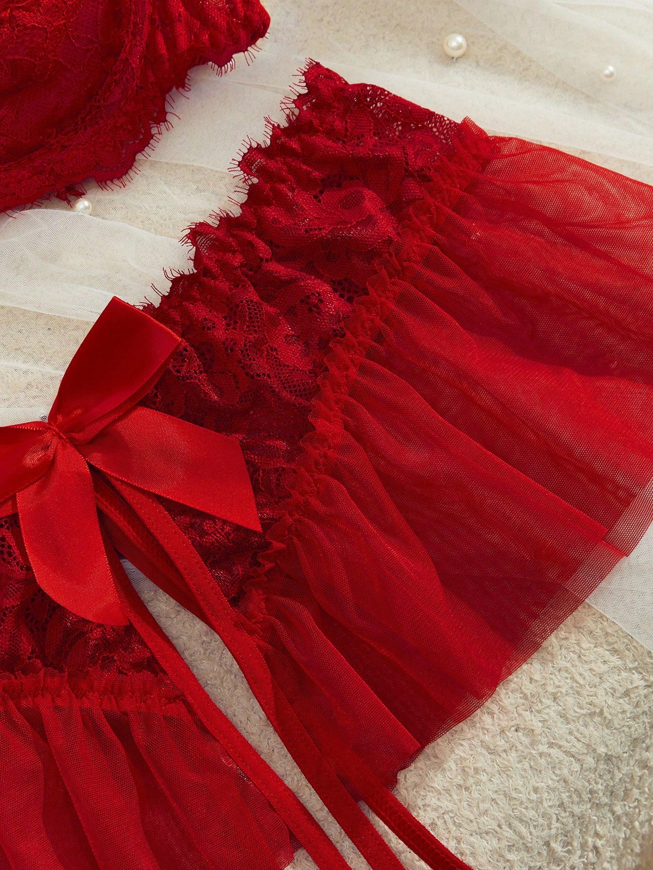 Semi-sheer red lace babydoll lingerie set featuring a flowy ruffle-hem skirt, spaghetti straps, underwire bralette top, and matching low-rise thong.
