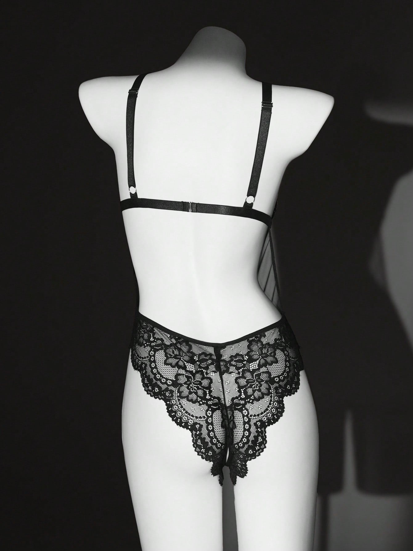 Women’s one-piece lace bodysuit with patchwork design, criss-cross detail, cut-out accents, spaghetti straps, and a semi-sheer look.