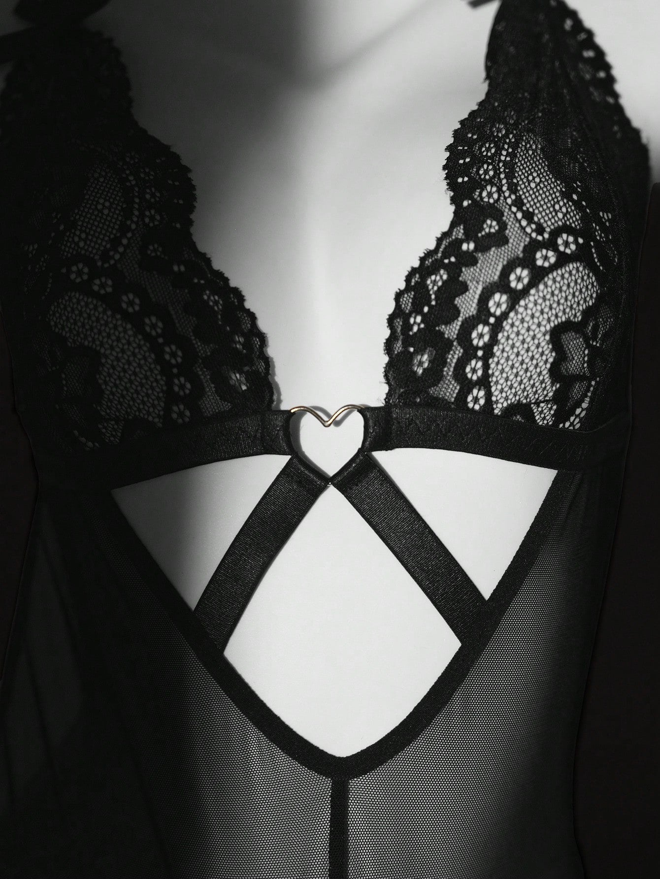 Women’s one-piece lace bodysuit with patchwork design, criss-cross detail, cut-out accents, spaghetti straps, and a semi-sheer look.