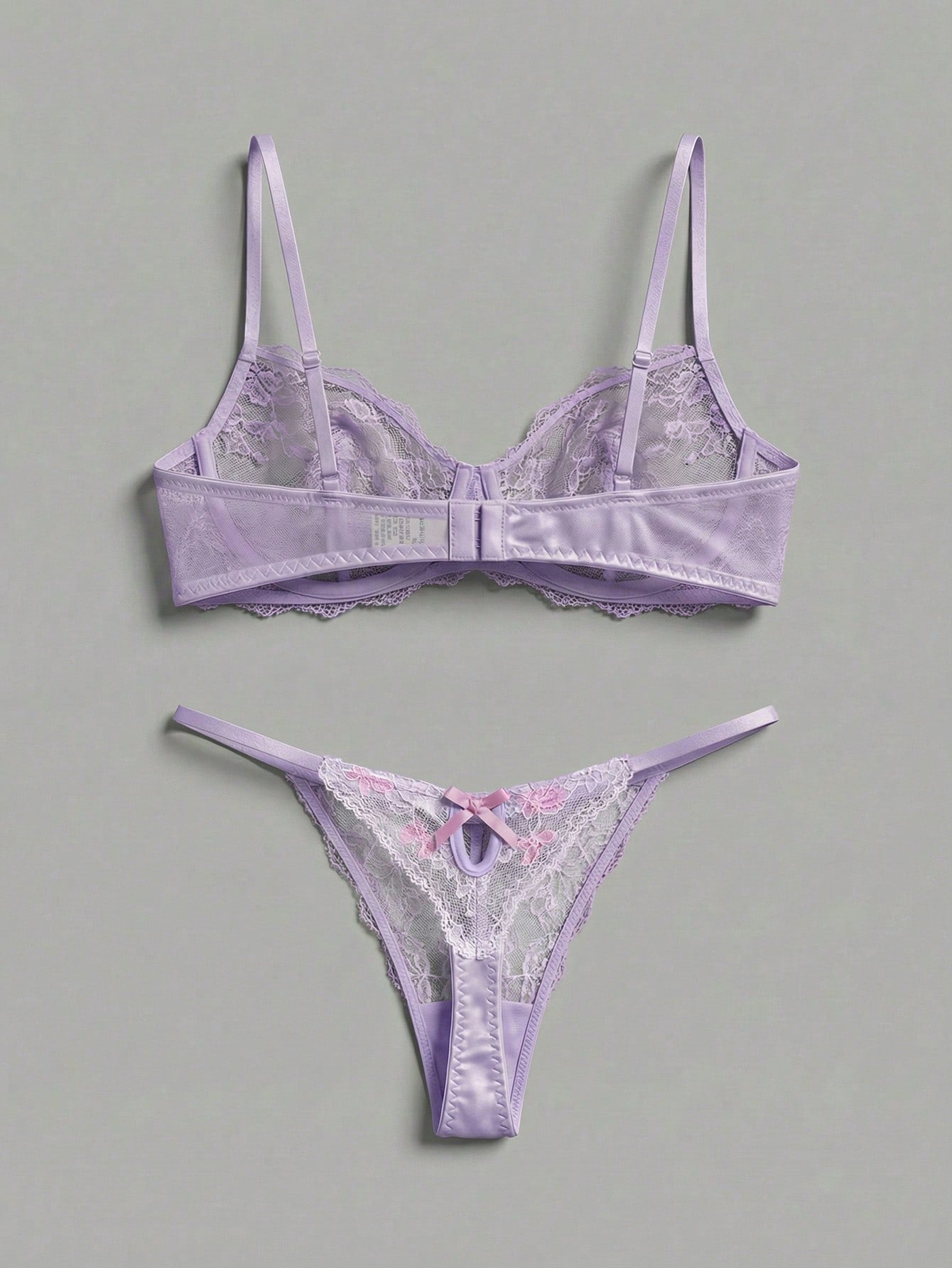 Two-piece pink lingerie set featuring a sheer mesh underwire bra with floral embroidery and adjustable straps, paired with a matching low-rise thong.