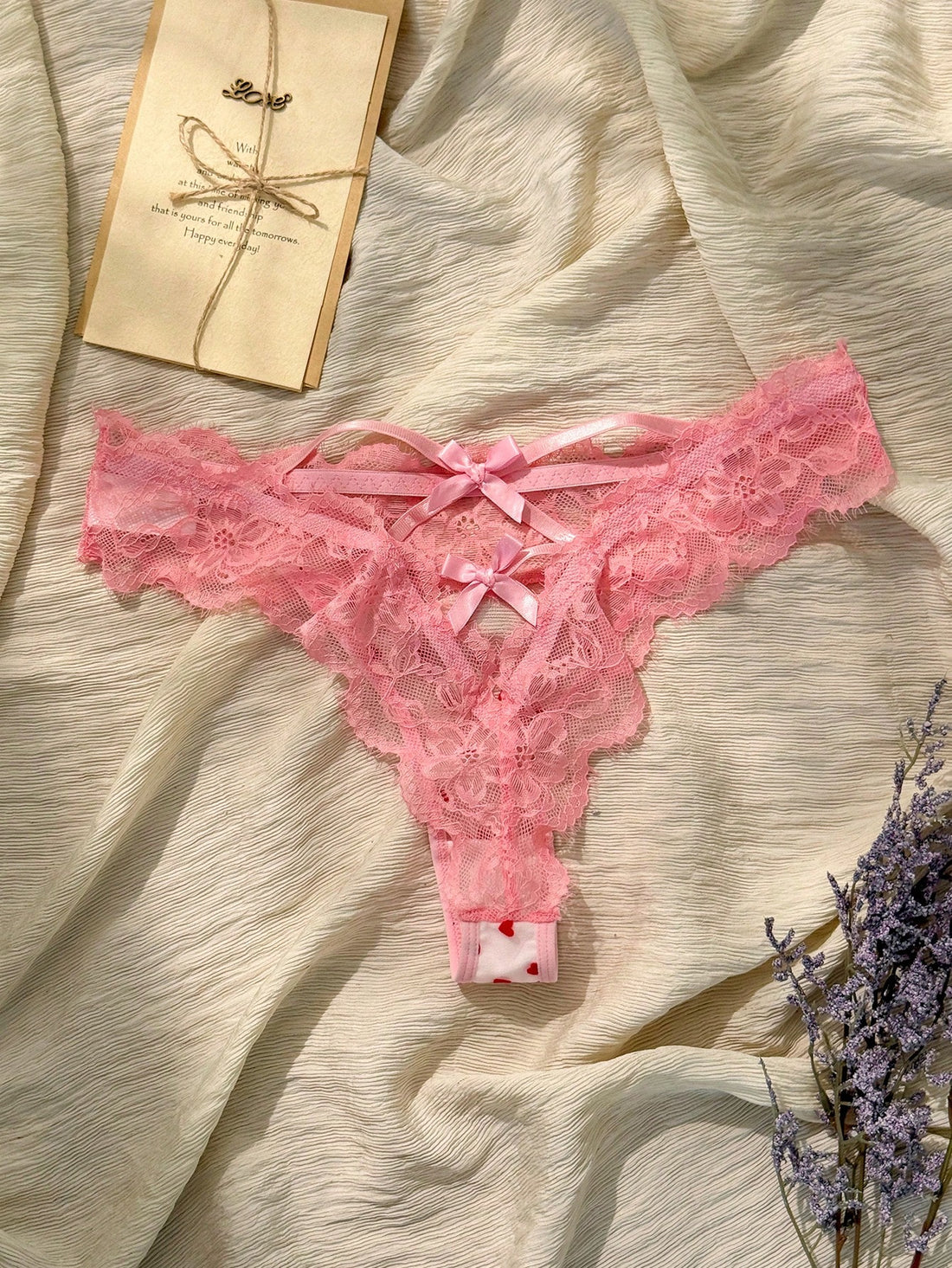 Women's pink heart flocked thong panties with sheer detailing, lace trim, geometric pattern accents, and a mid-rise romantic-floral style.