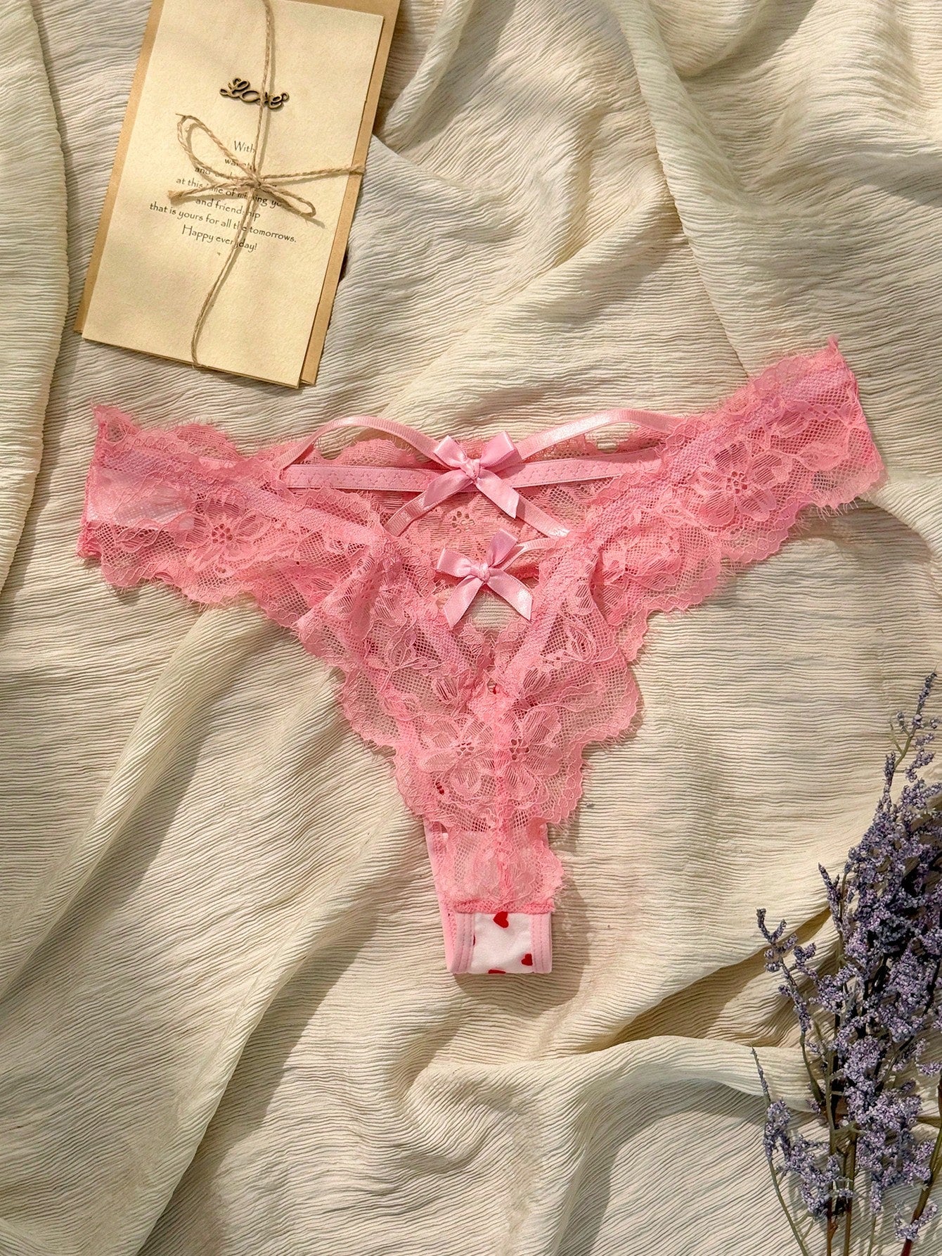 Women's pink heart flocked thong panties with sheer detailing, lace trim, geometric pattern accents, and a mid-rise romantic-floral style.