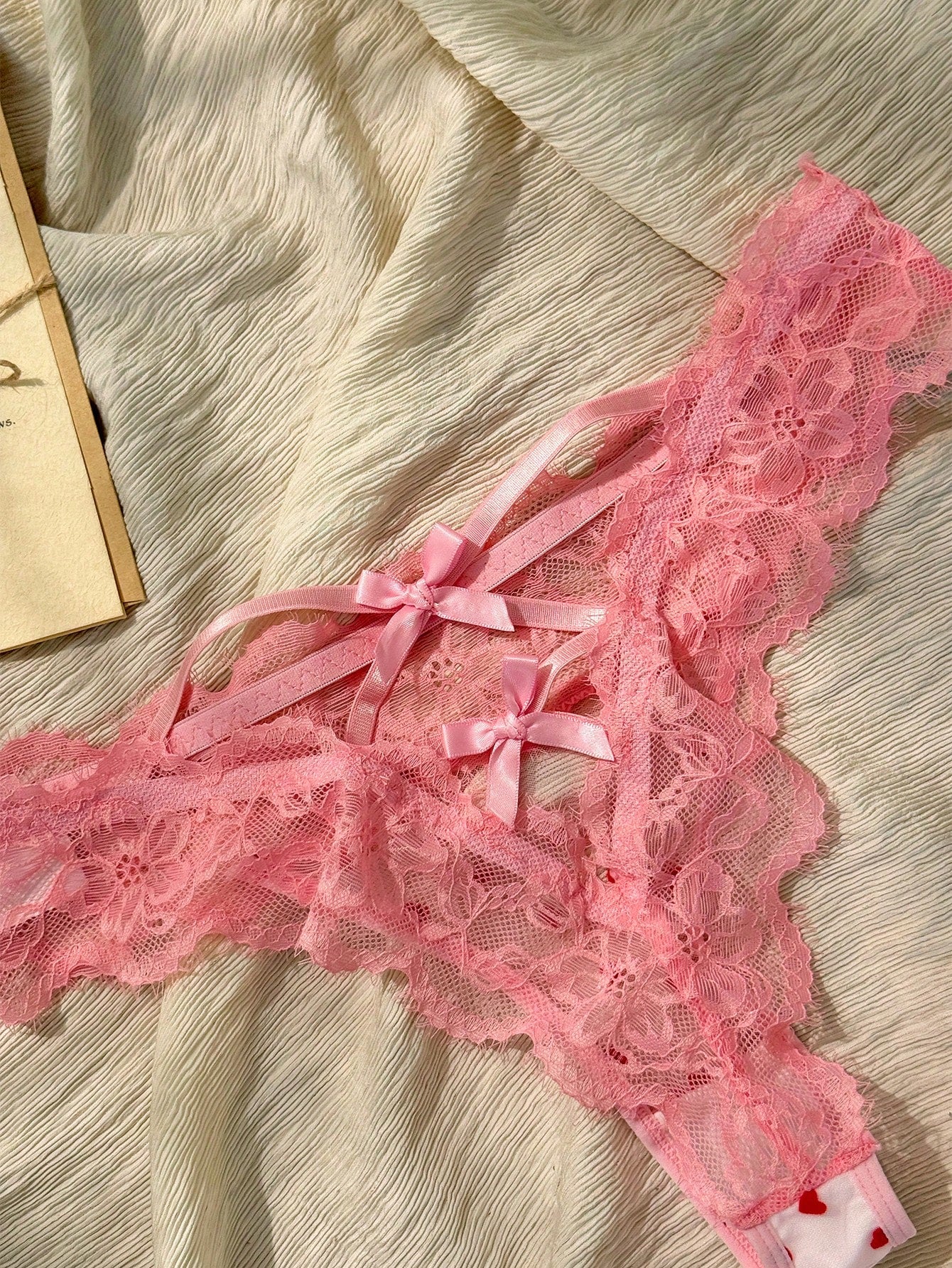 Women's pink heart flocked thong panties with sheer detailing, lace trim, geometric pattern accents, and a mid-rise romantic-floral style.