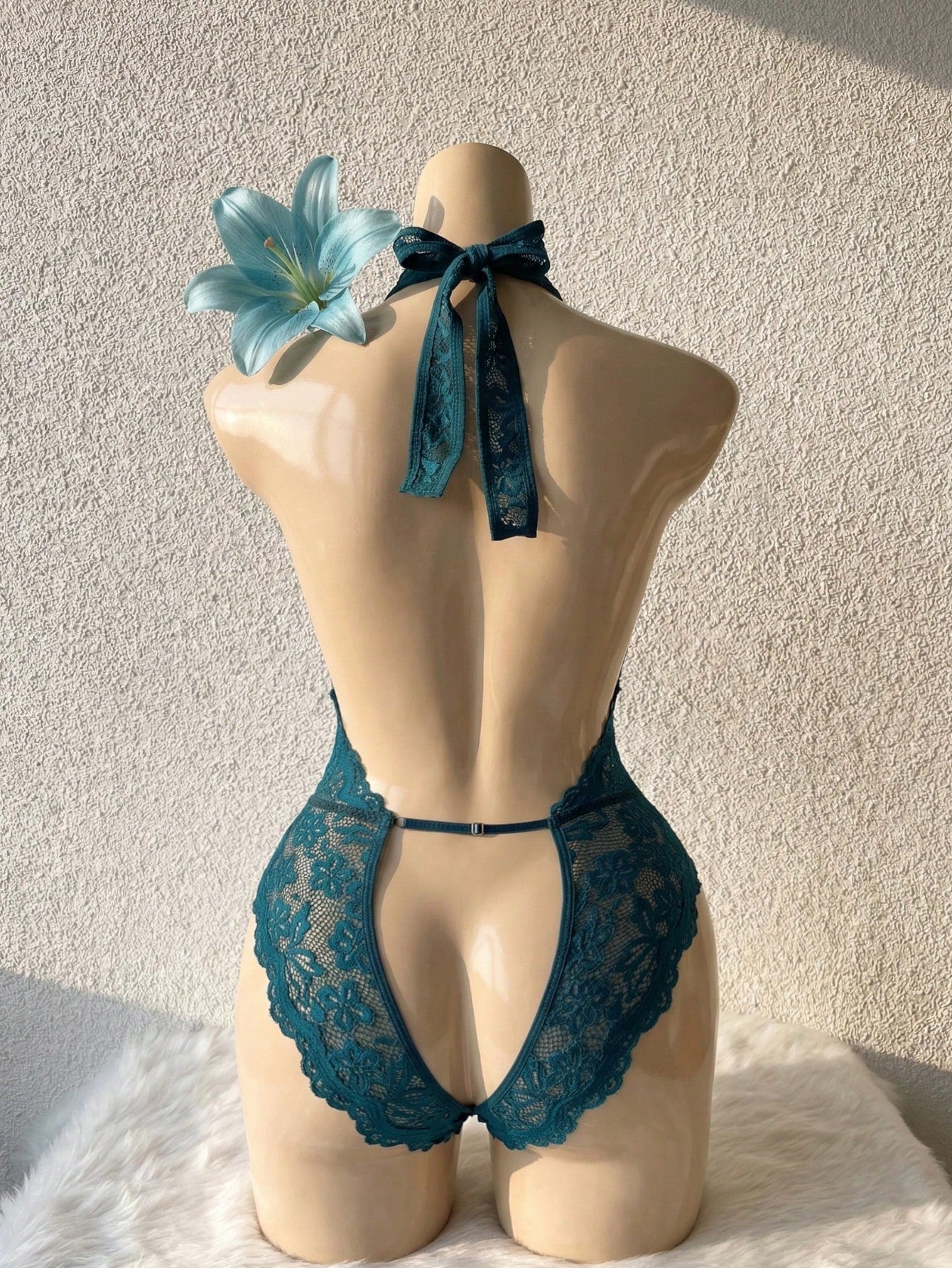 Teal blue floral lace crotchless teddy bodysuit lingerie with scallop trim, halter neckline, crossback straps, sheer unlined design, triangle cups, and thong-style low-rise bottom.